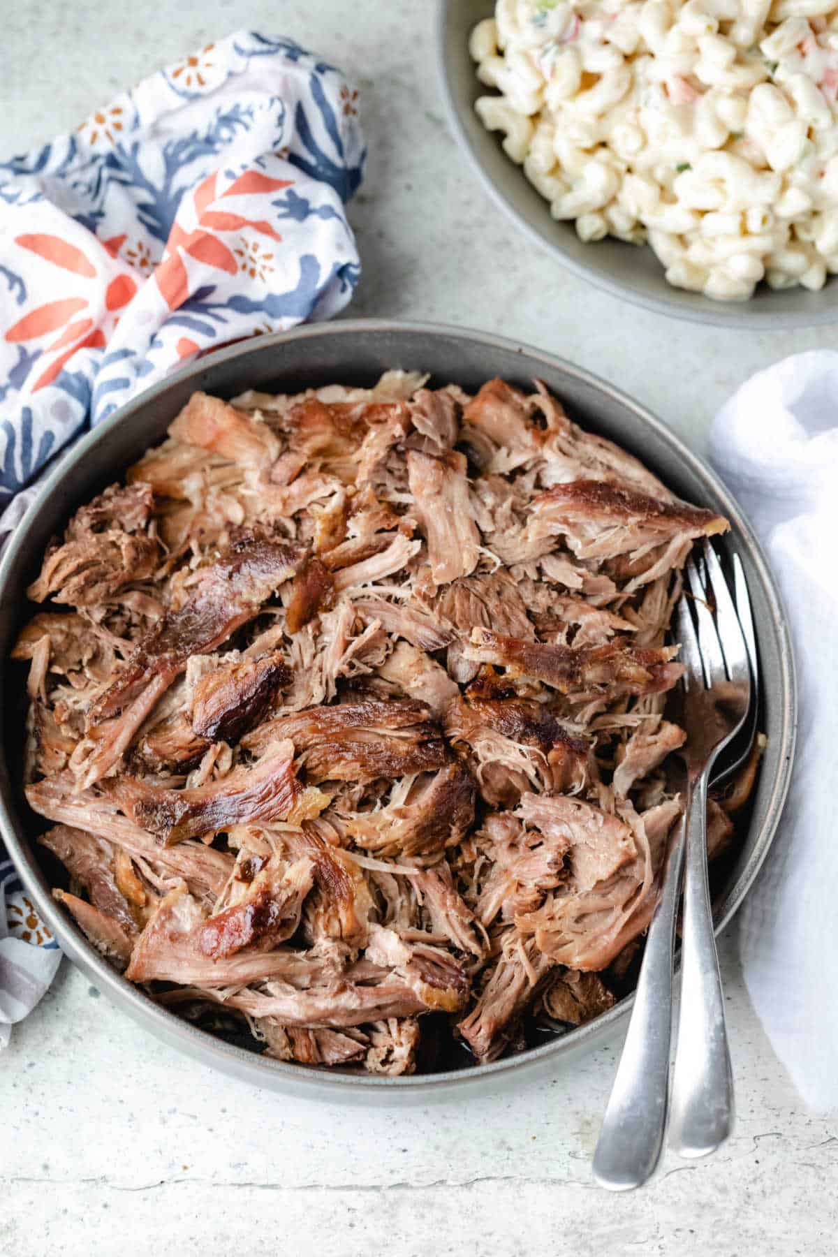 Dish of kalua pork next to a flowered napkin.