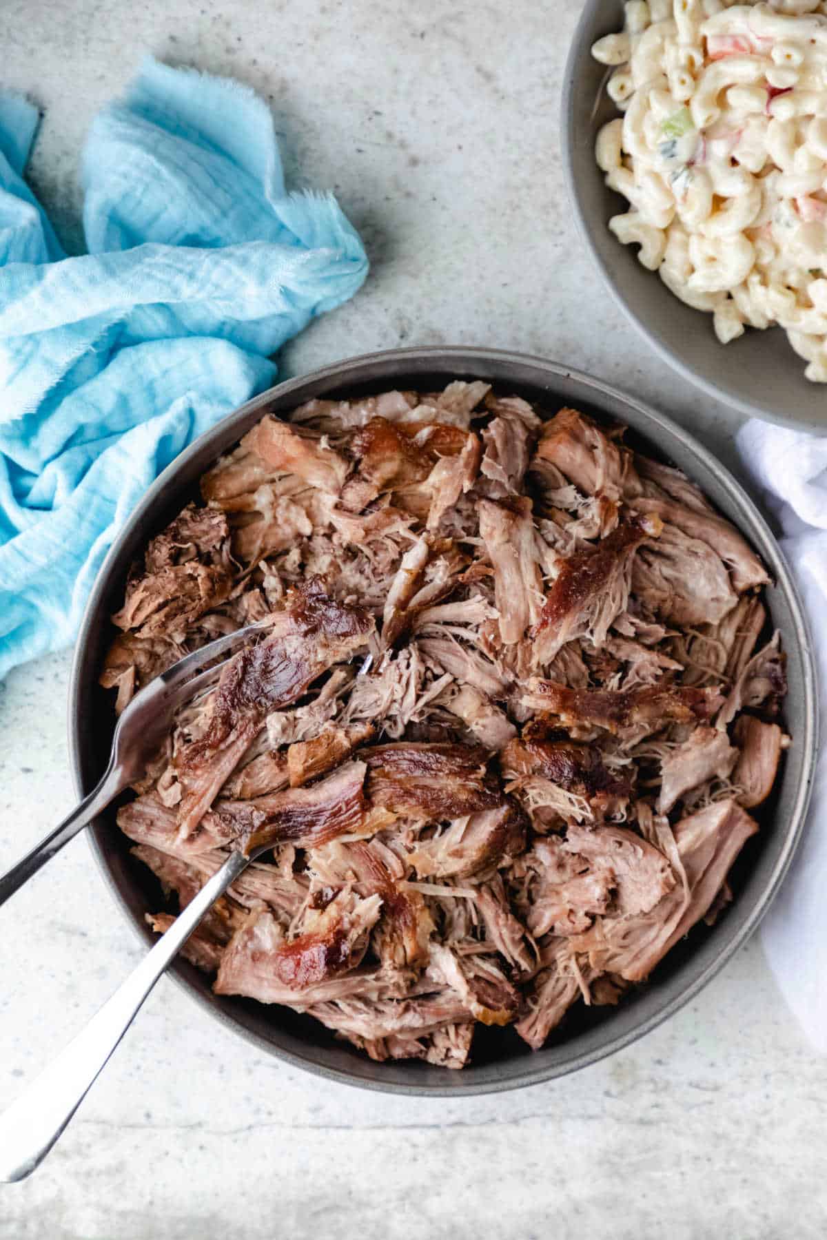 Bowl of kalua pork next to a blue napkin.