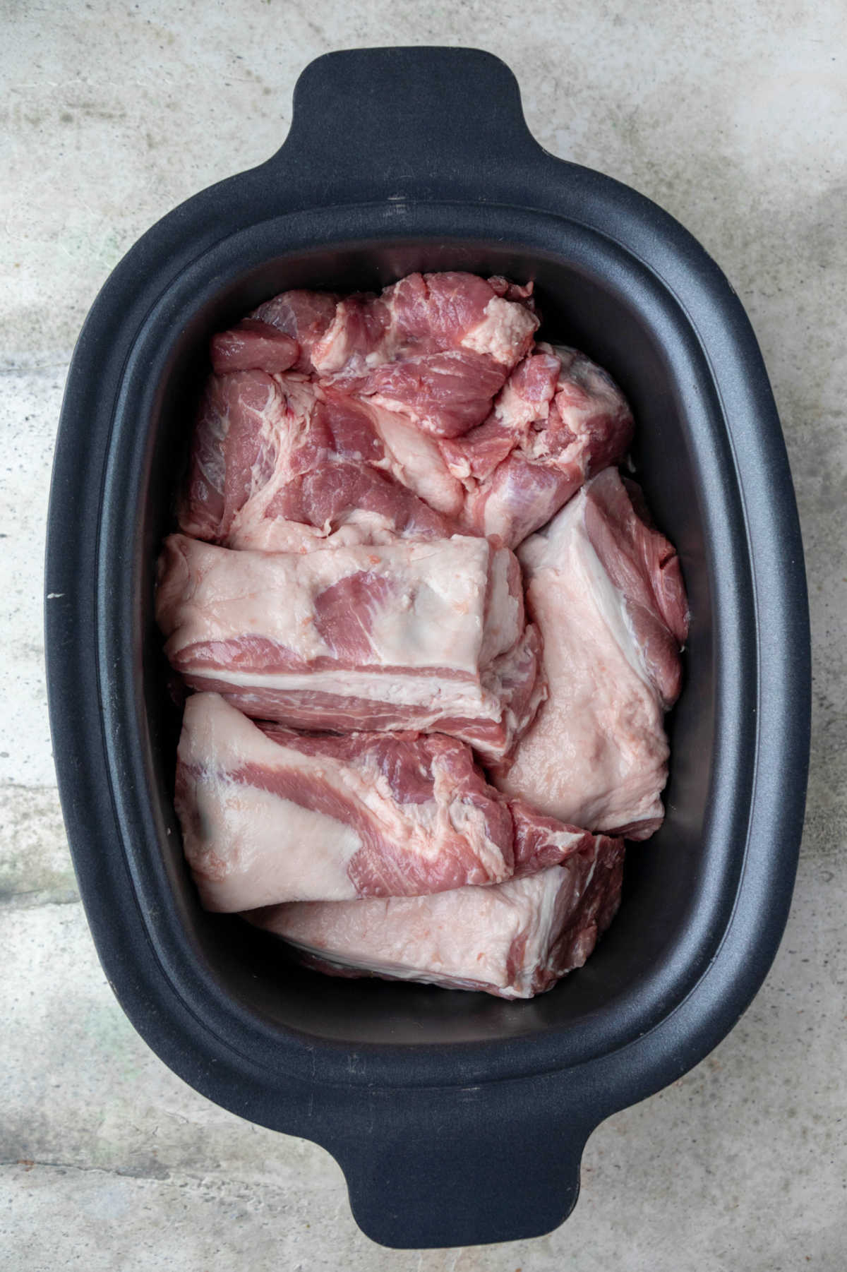 Pieces of pork roast in a slow cooker insert. 