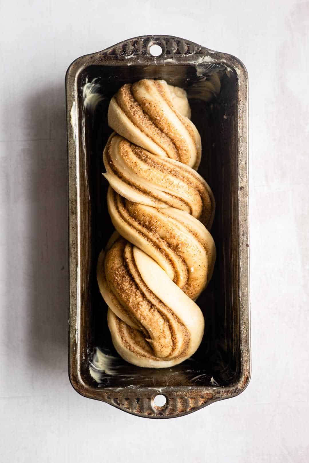 Unbaked loaf of cinnamon twist bread in a loaf pan.