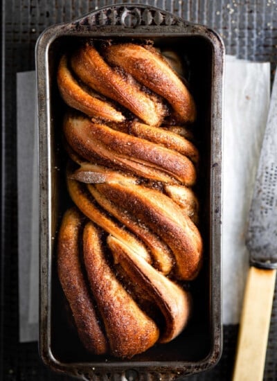 Loaf of cinnamon twist bread in a loaf pan.