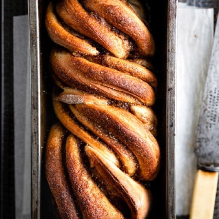 Loaf of cinnamon twist bread in a loaf pan.