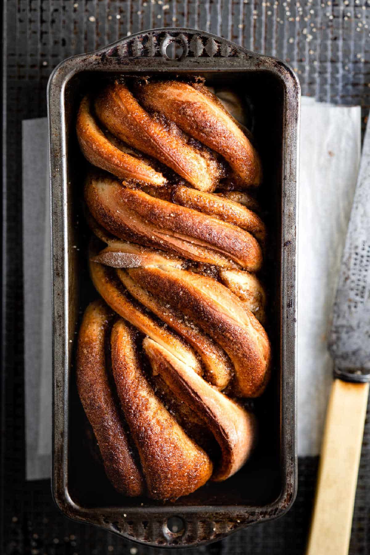 Loaf of cinnamon twist bread in a loaf pan.