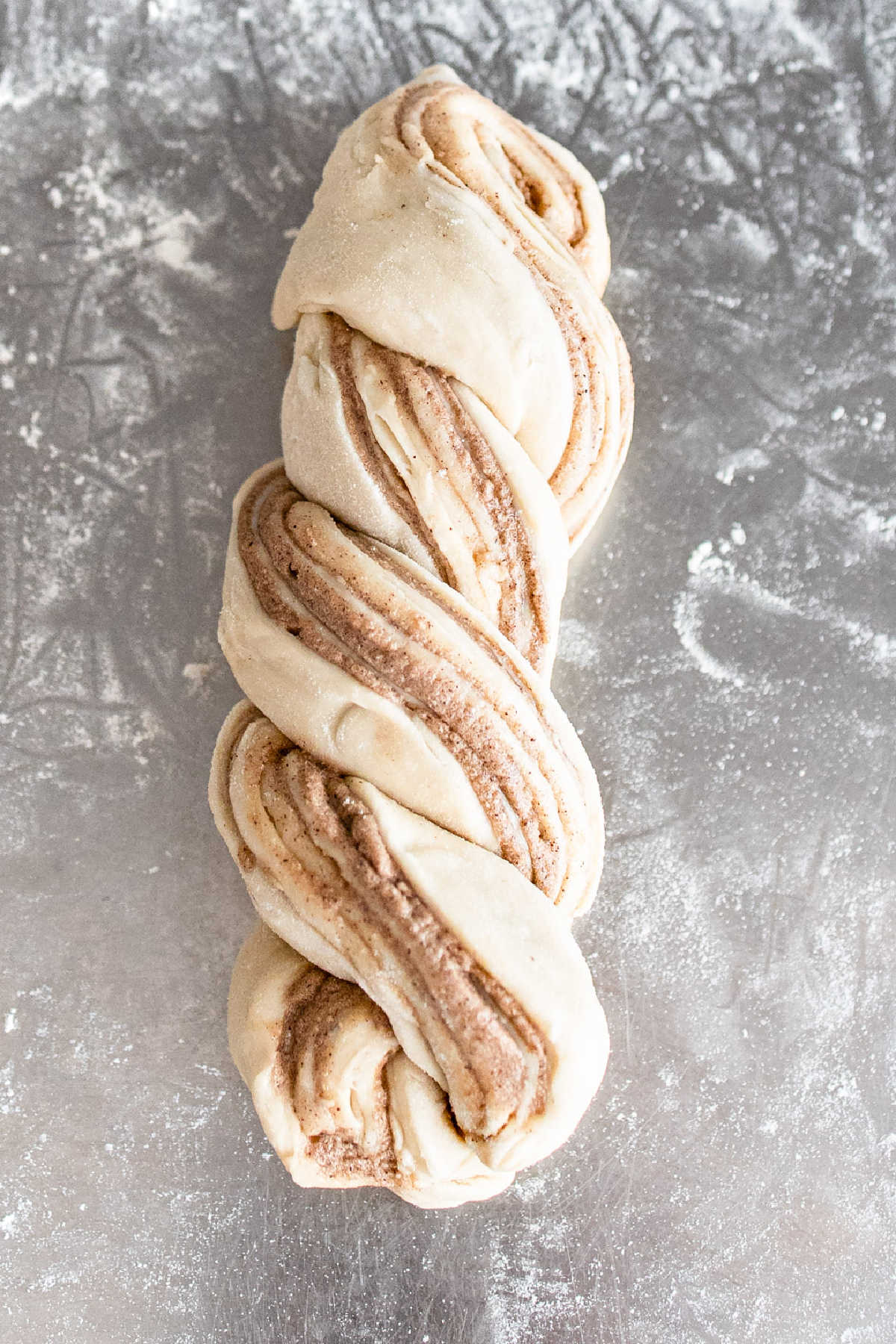 Twisted loaf of cinnamon bread on a floured surface.