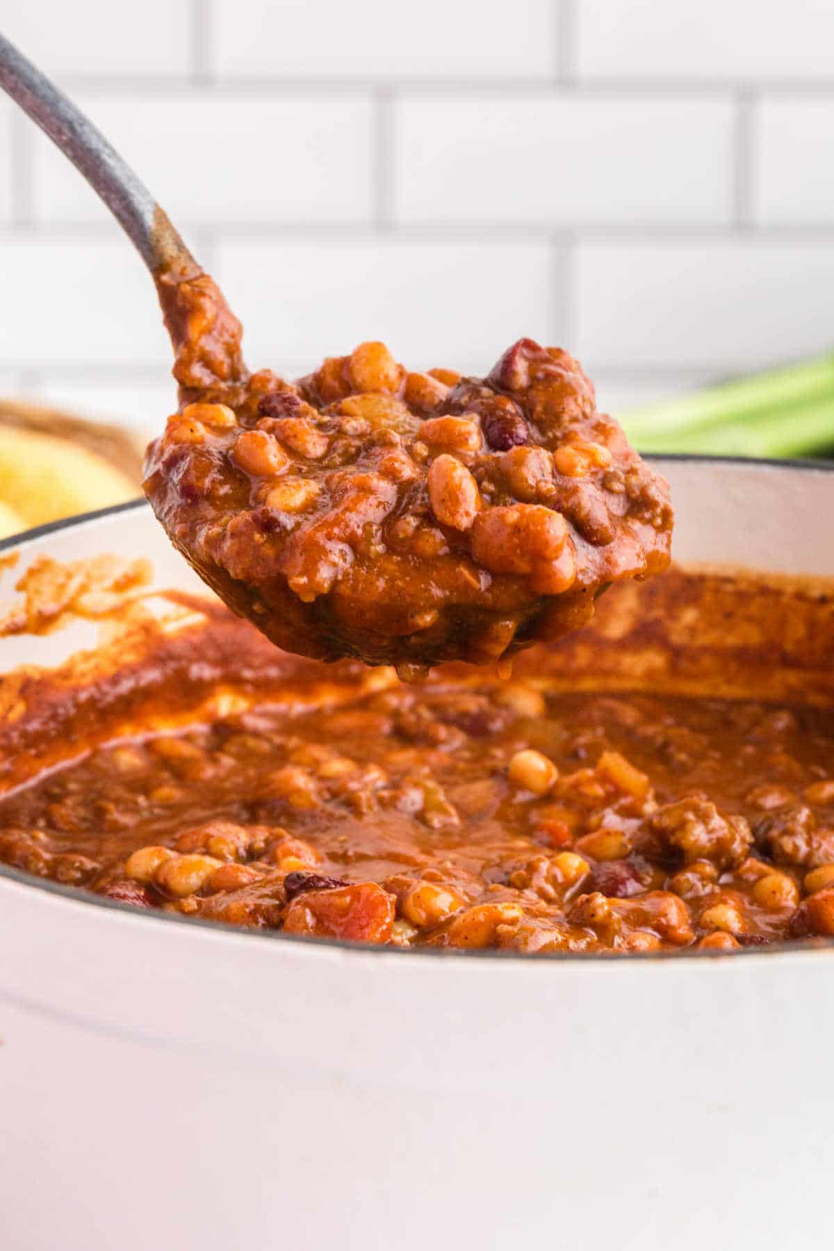 Spoon lifting a scoop of chili out of a pot.