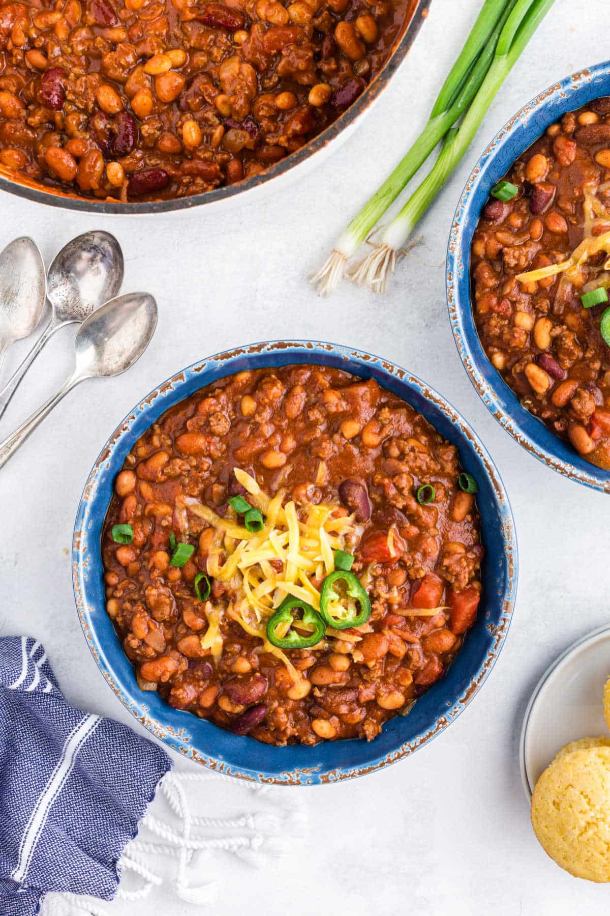 Bowl of chili topped with grated cheese and jalapeno slices. 