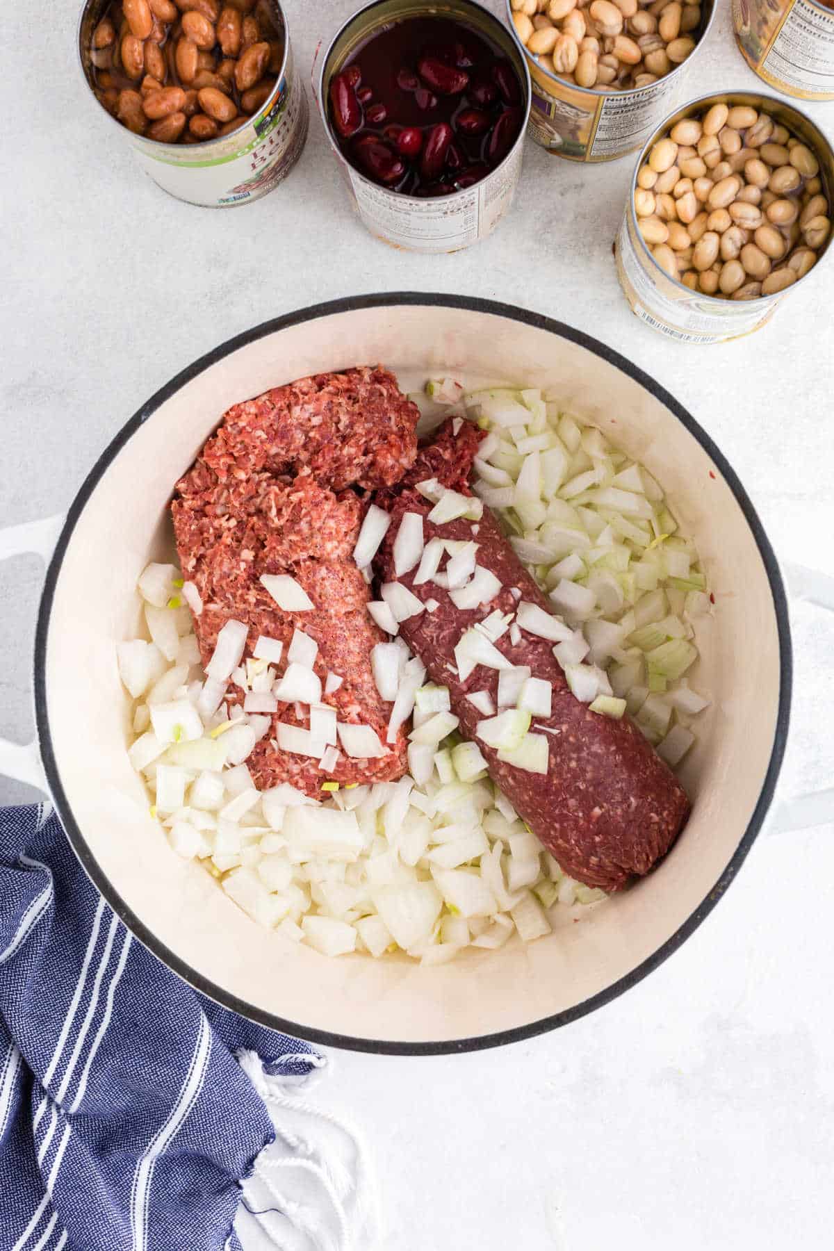 Diced onion sausage and ground beef in a Dutch oven.