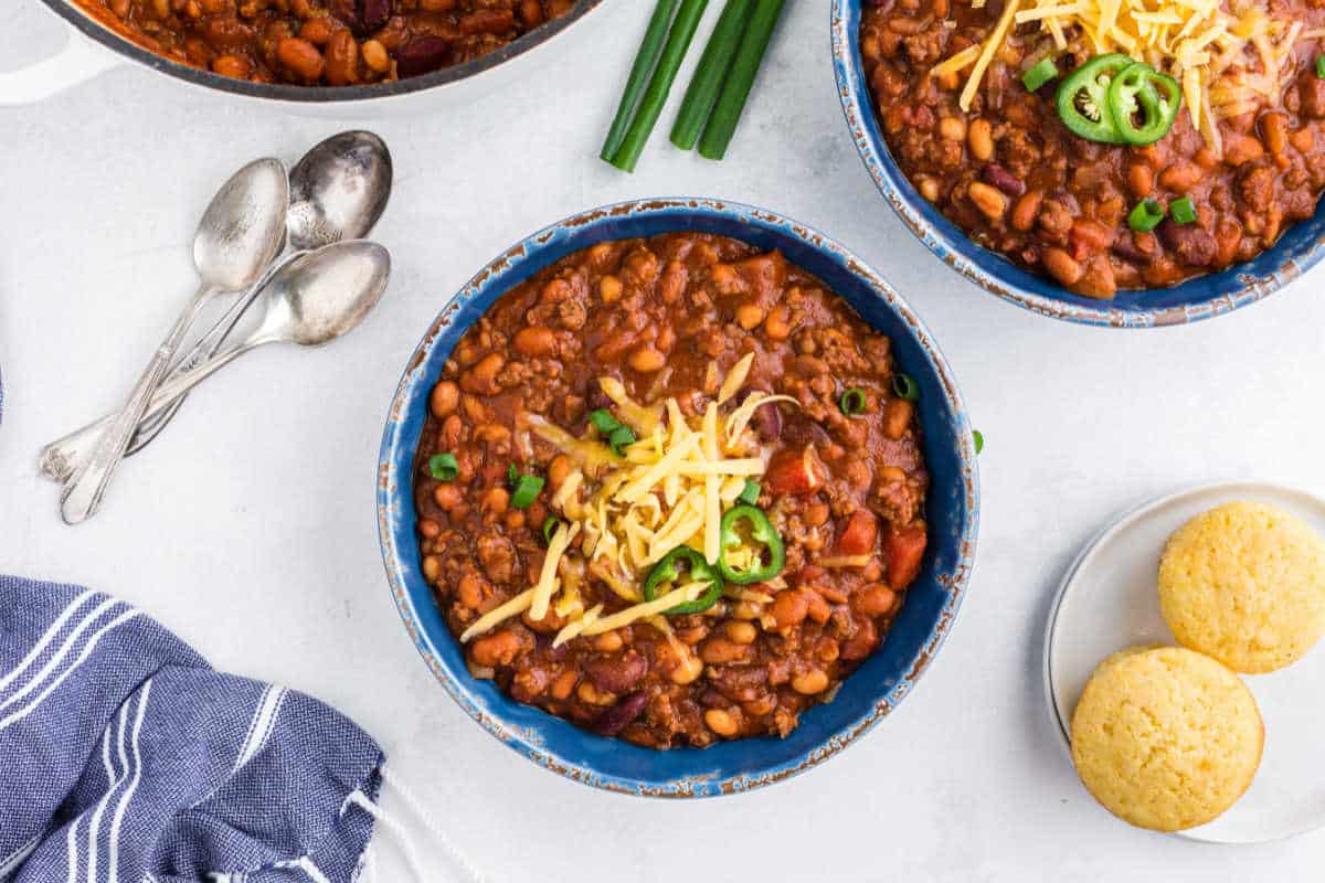 Bowls of chili next to spoons.