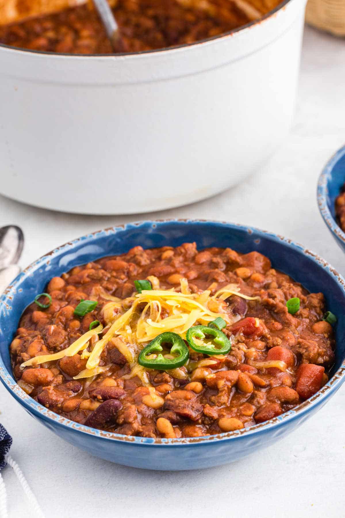 Chili in a blue bowl next to a pot of chili.