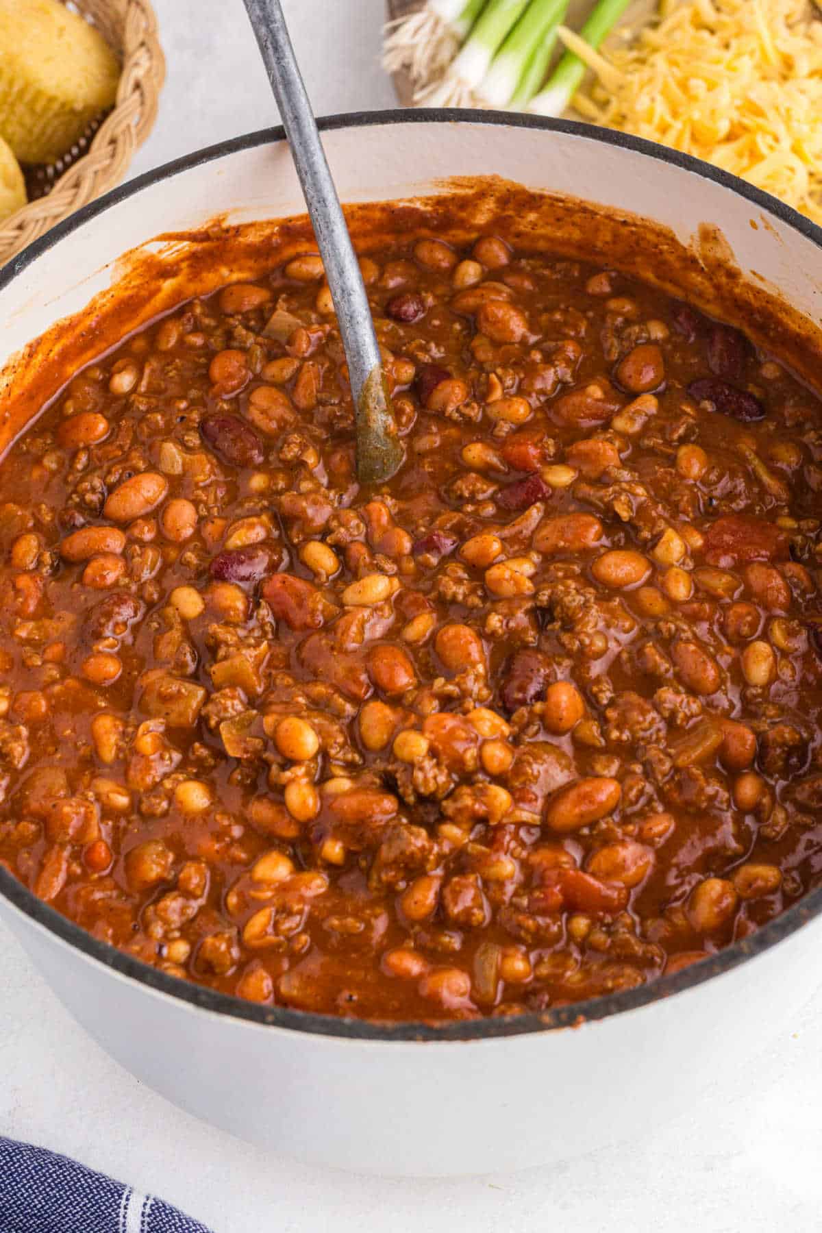 A spoon stirring a pot of chili.