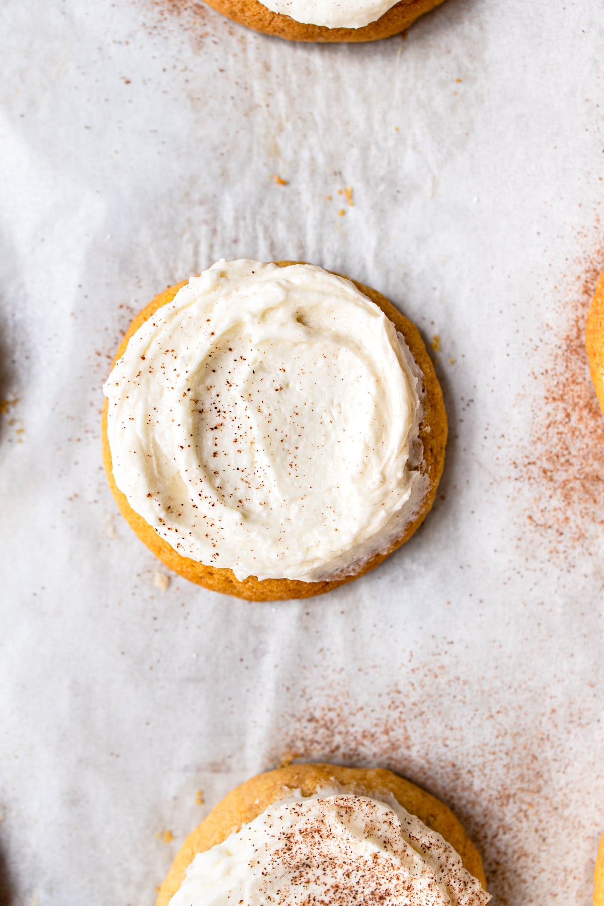 Frosted pumpkin cookie dusted with cinnamon.