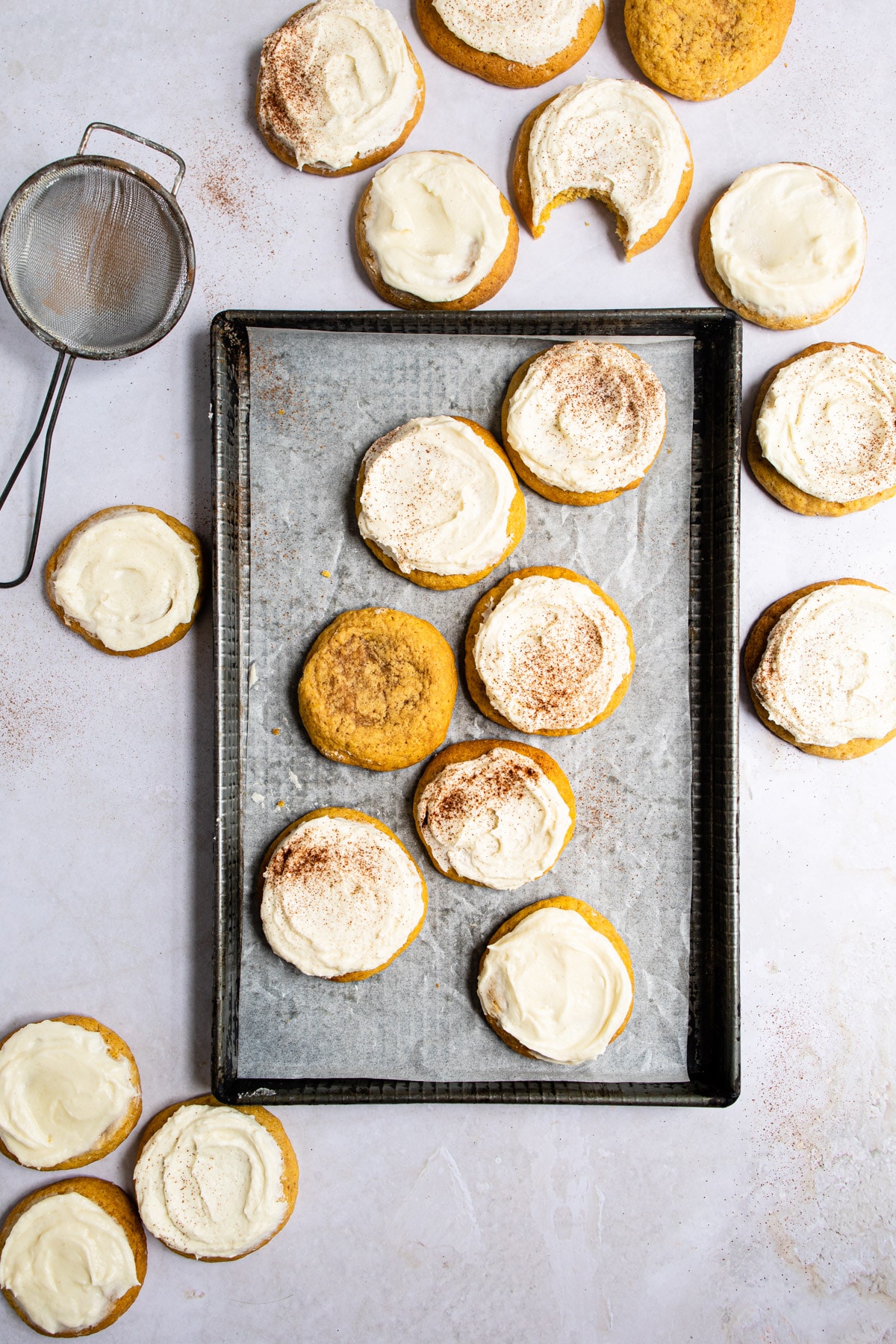 Frosted pumpkin cookies on a baking tray.