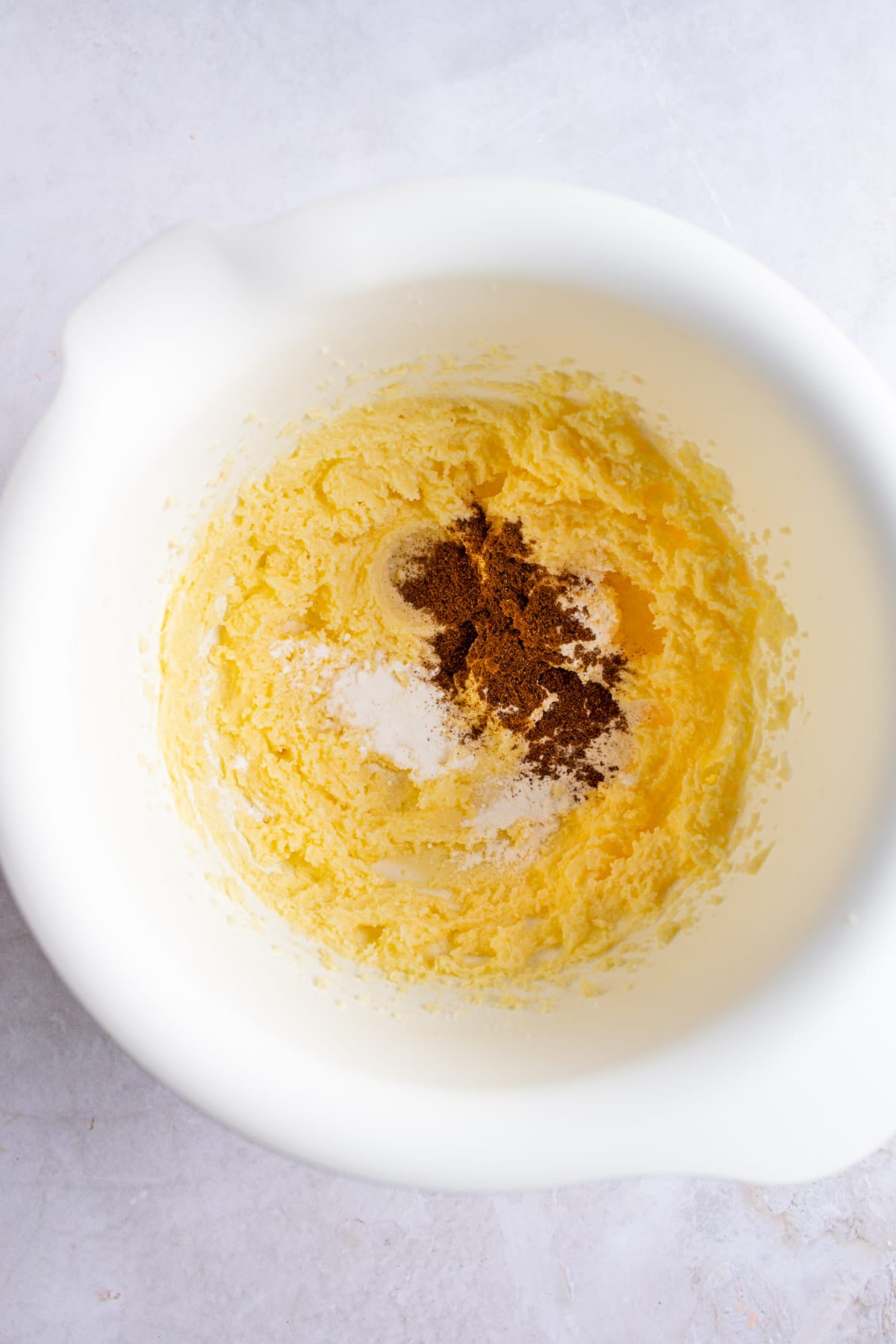 Beaten butter and spices in a white mixing bowl.