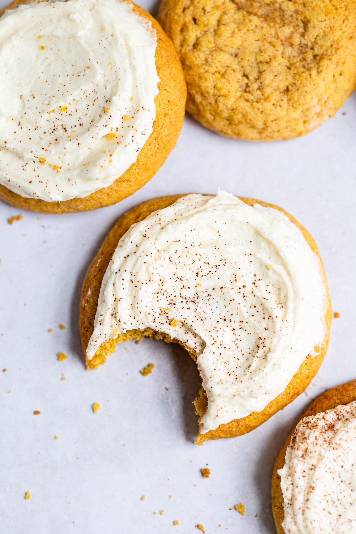 Frosted pumpkin cookies with a bite out of it. 