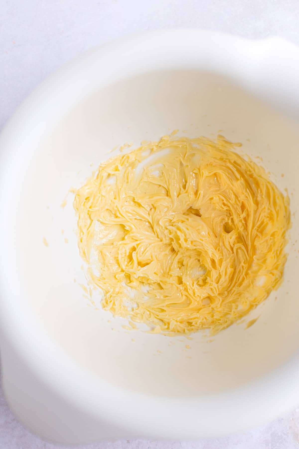 Beaten butter in a white mixing bowl. 