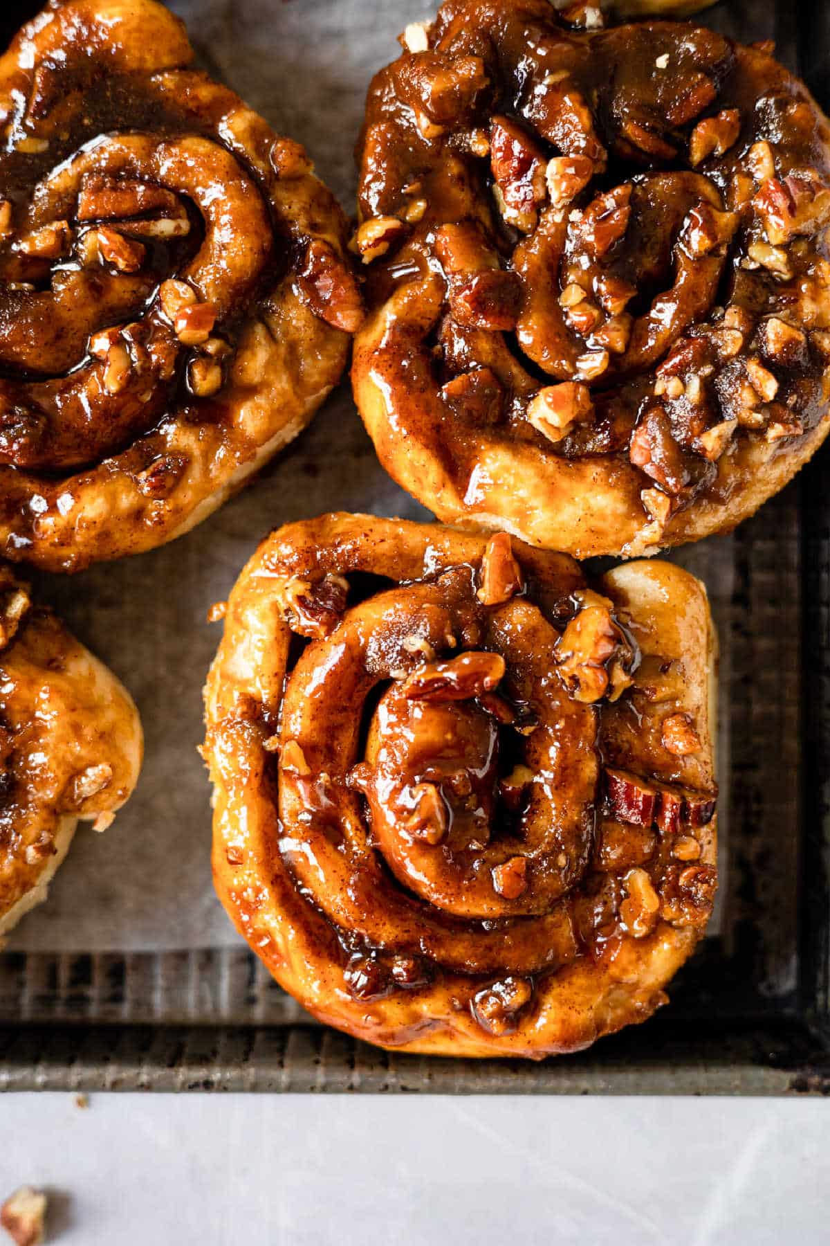 Homemade caramel rolls on a dark metal baking sheet. 