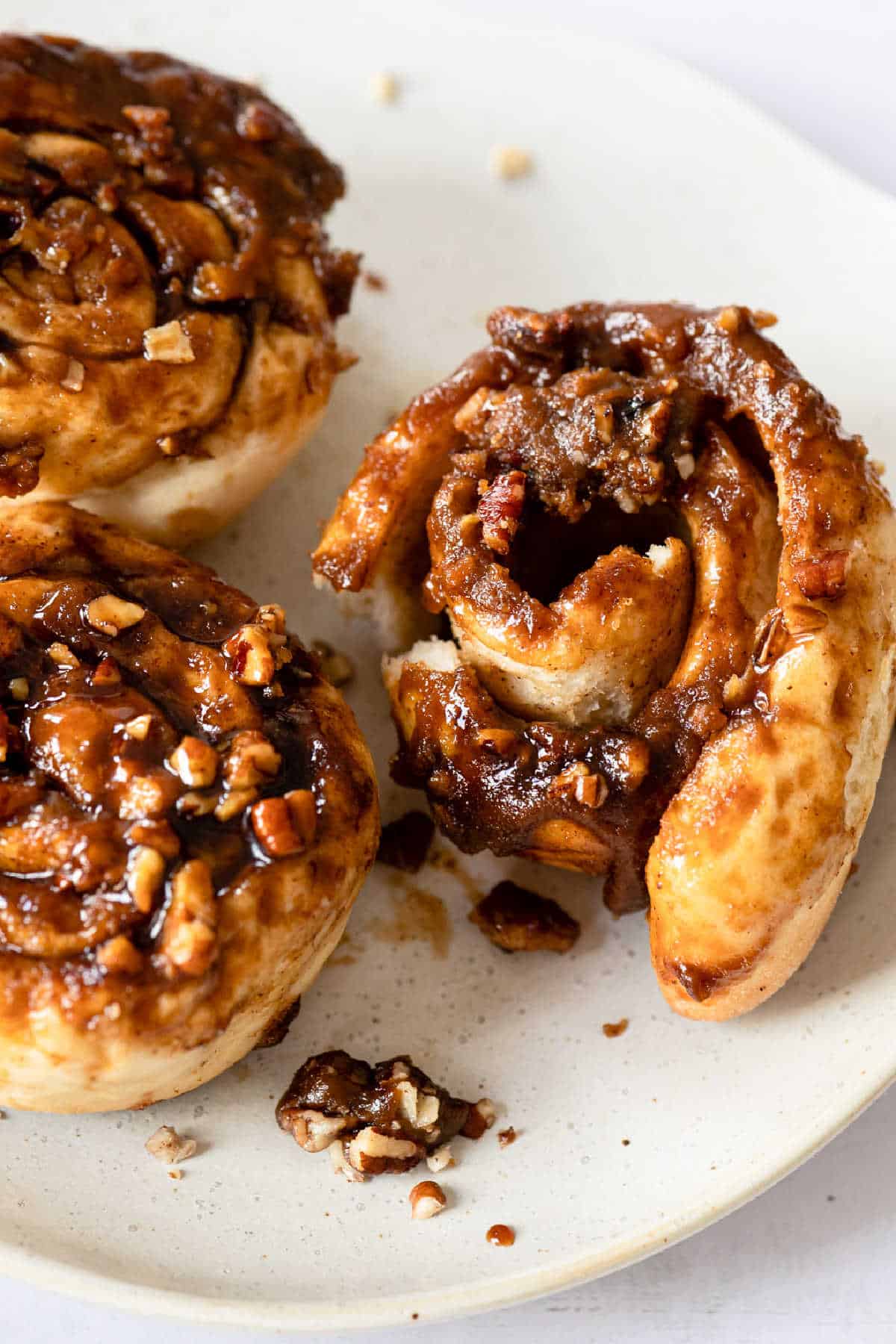 Caramel roll on a plate with a bite missing.