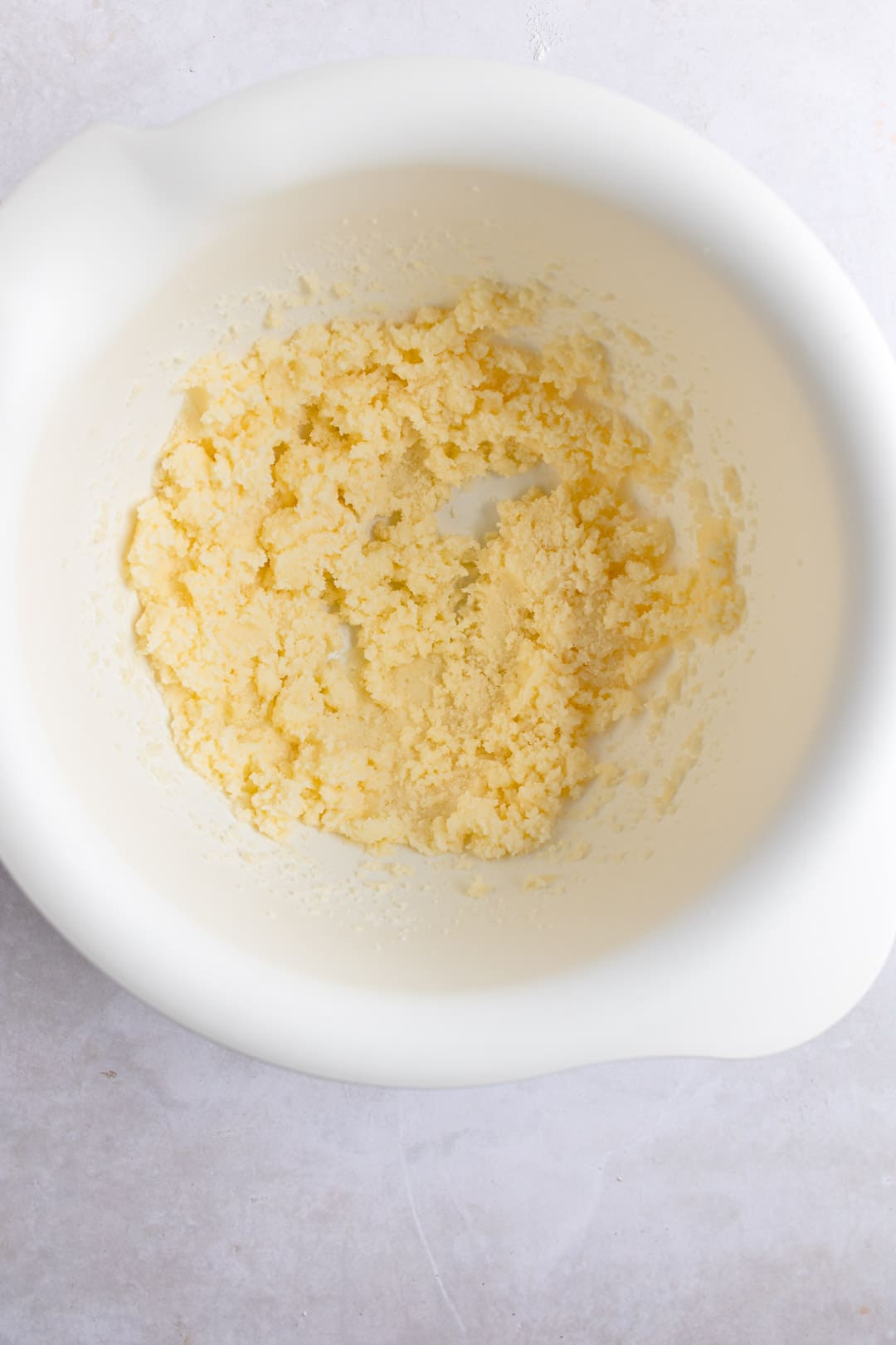 Beaten butter in a white mixing bowl. 