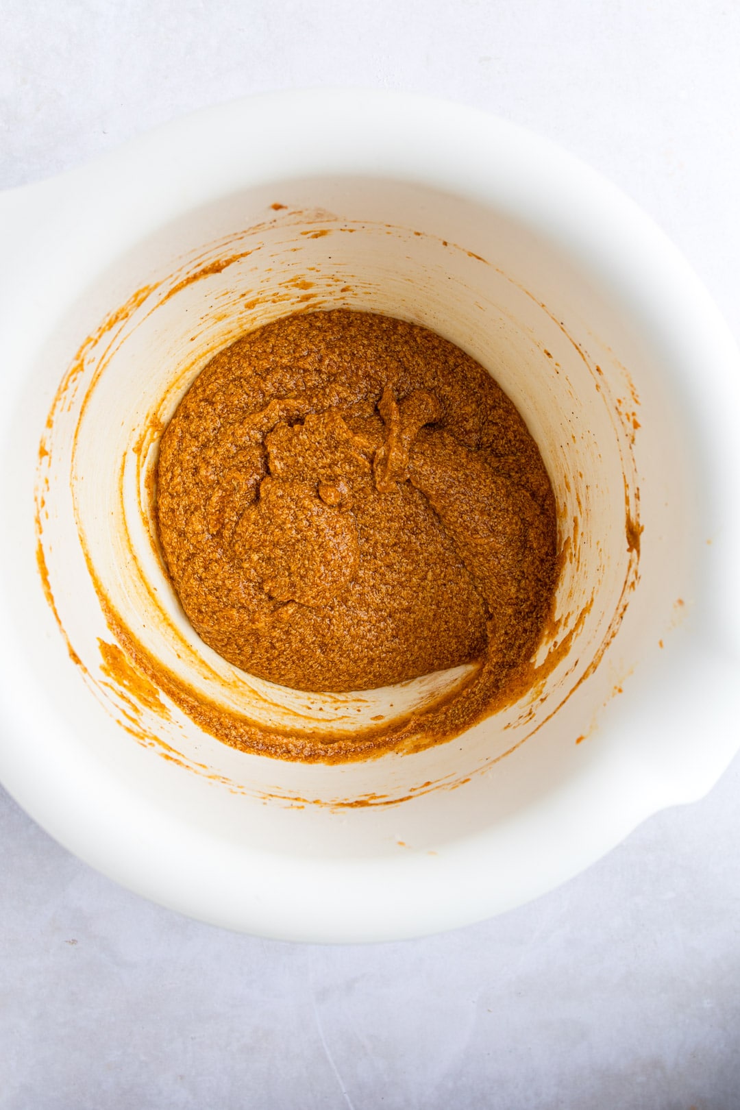 Pumpkin chocolate chip cookie batter in a white mixing bowl. 