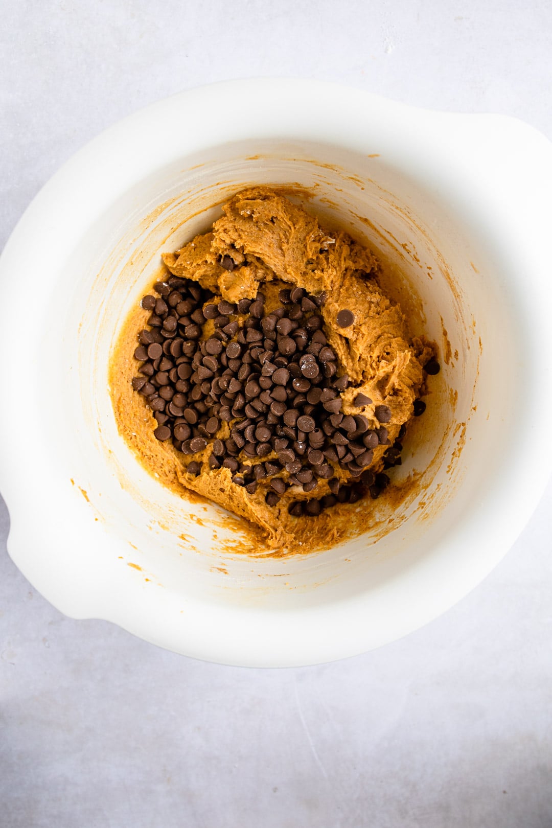 Chocolate chips on top of pumpkin cookie dough.