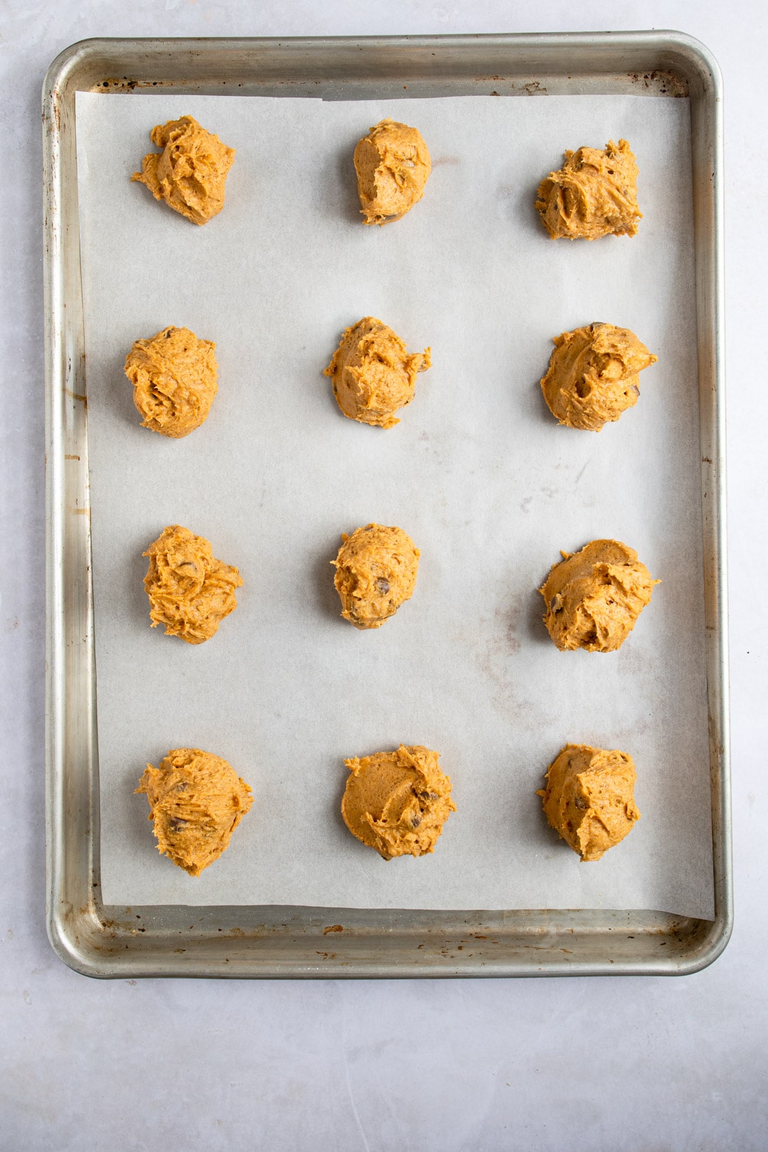 Unbaked pumpkin chocolate chip cookie dough on a cookie sheet. 