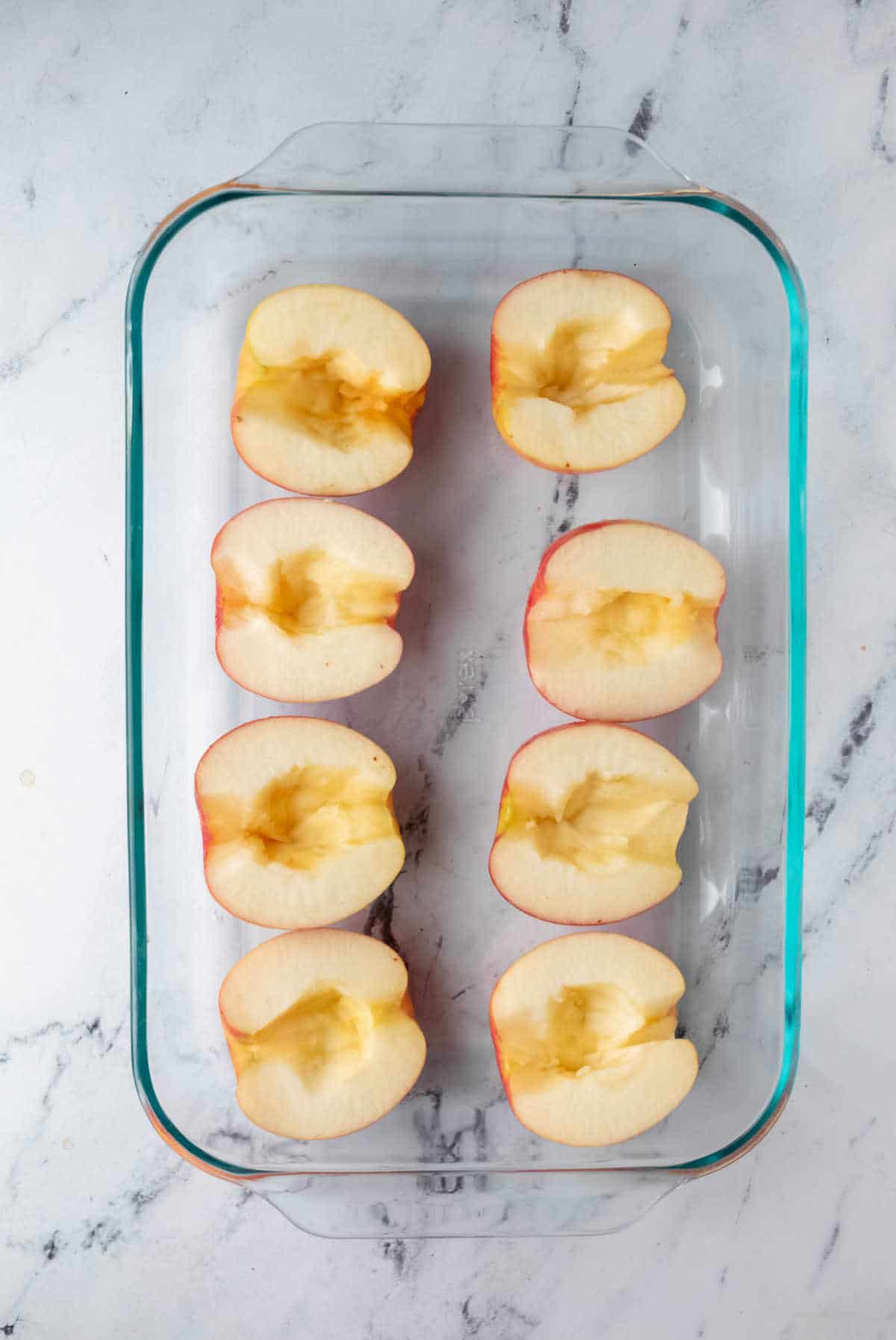 Halved apples in a glass pan.
