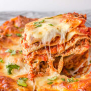 A piece of freezer lasagna being cut and lifted out of the pan.