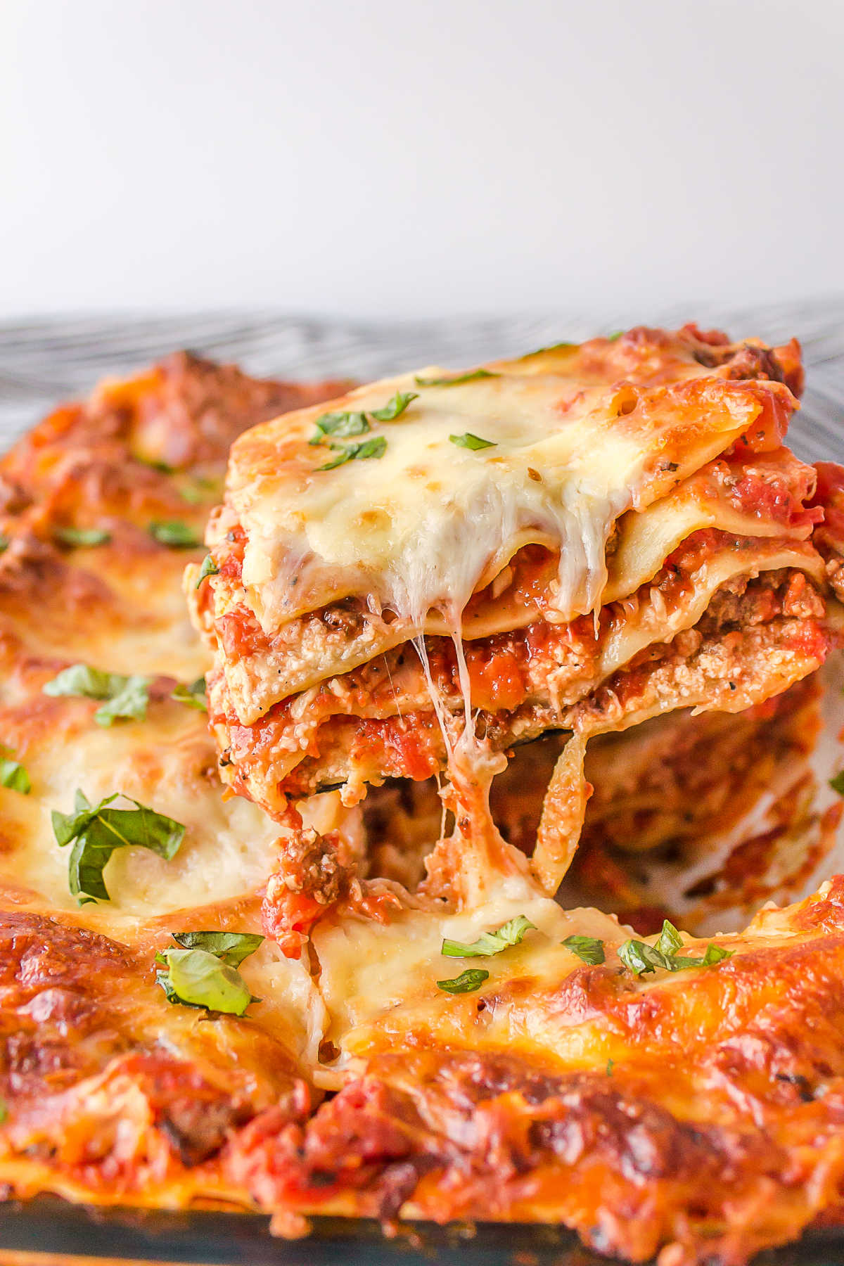 A piece of freezer lasagna being cut and lifted out of the pan.