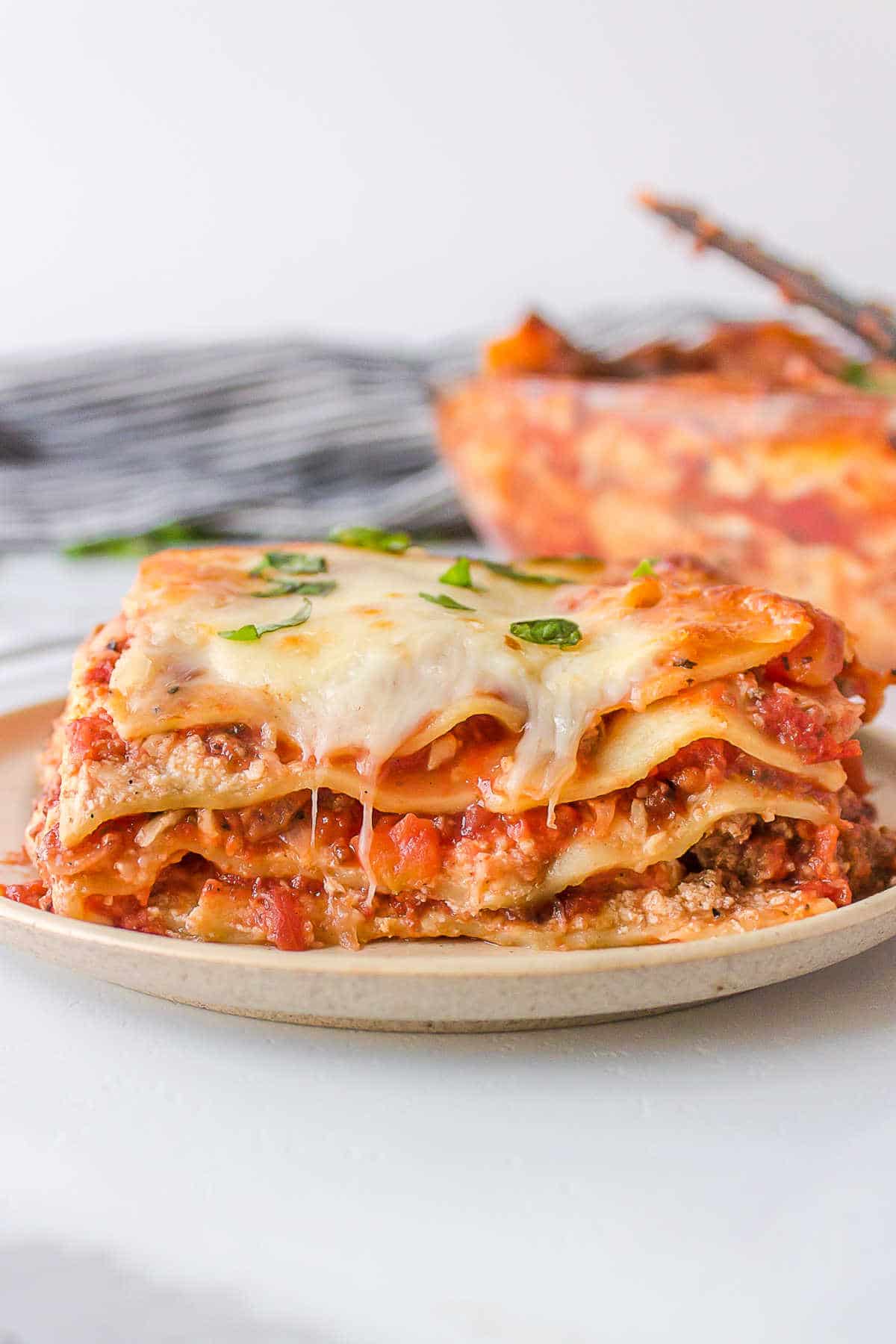 Slice of baked lasagna on a white plate. 