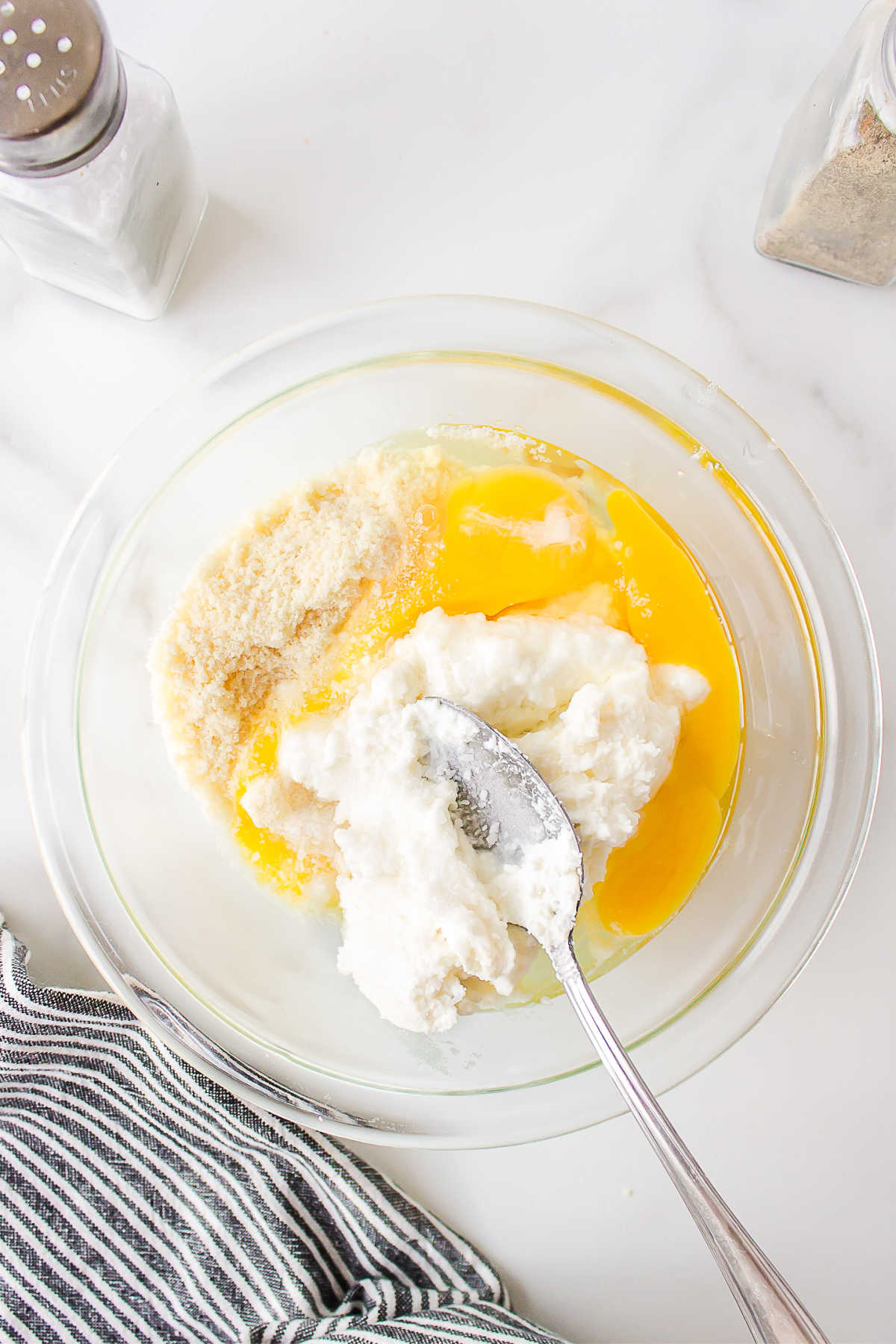Ricotta eggs and parmesan in a mixing bowl. 