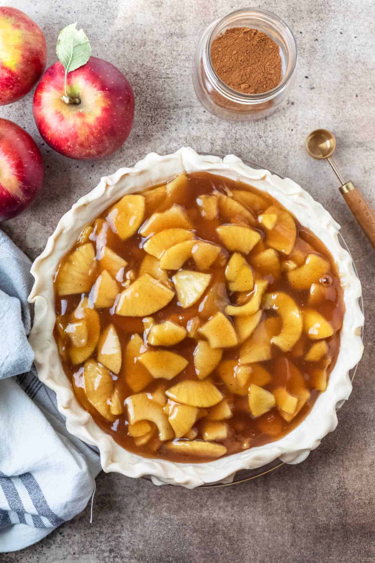 Unbaked apple pie next to apples. 