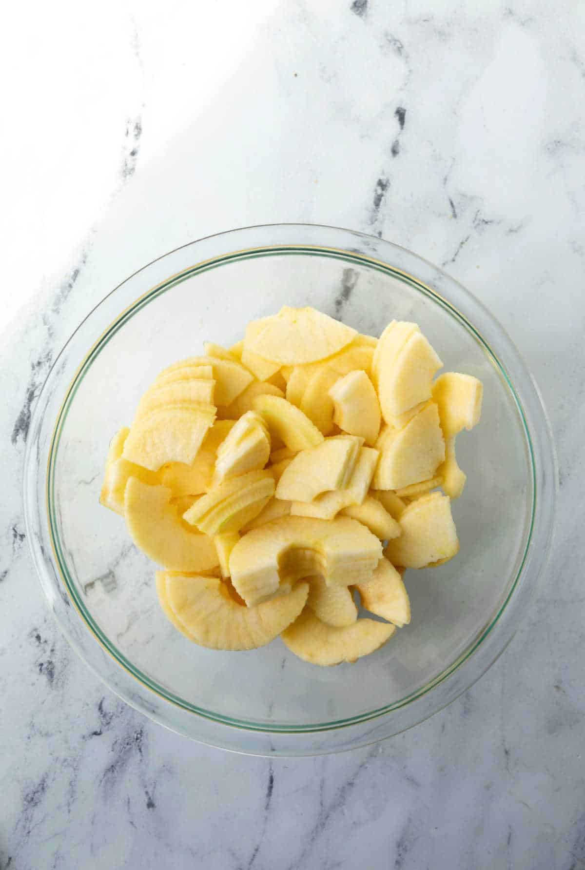 Apple slices in a glass mixing bowl. 