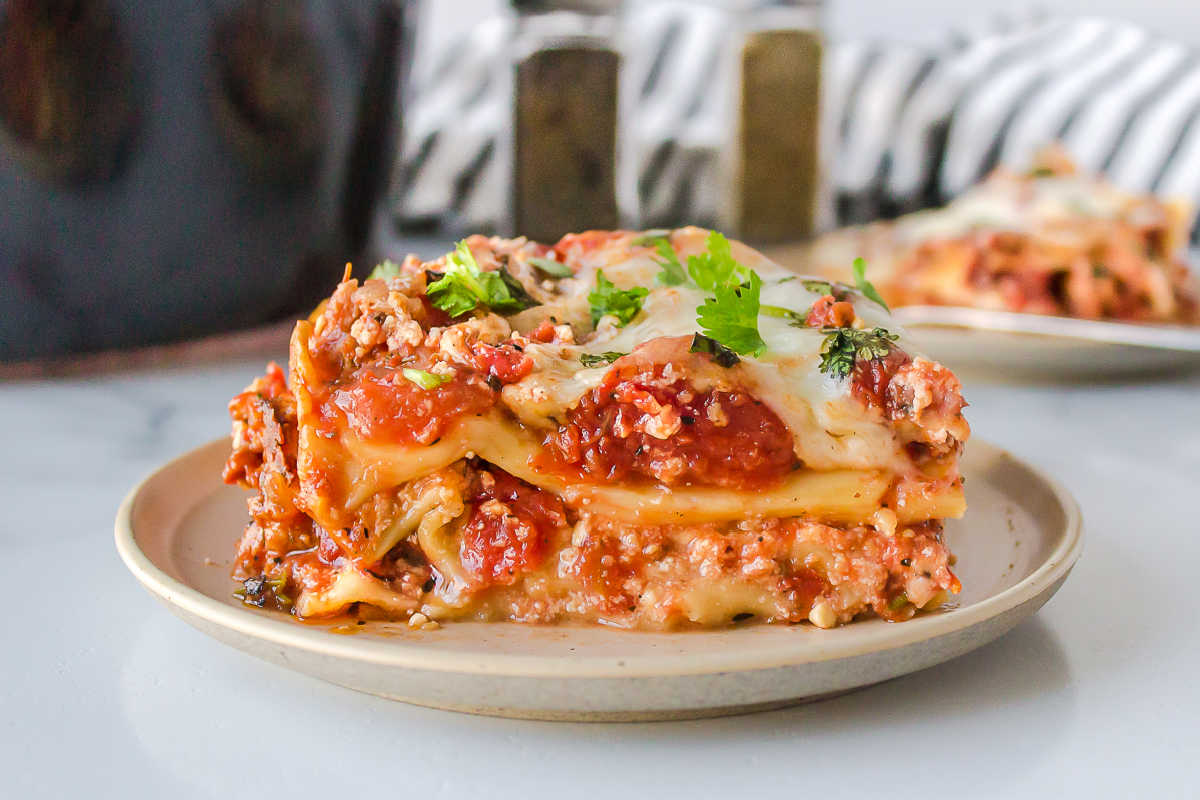 Plate with a slice of crock pot lasagna topped with parsley.