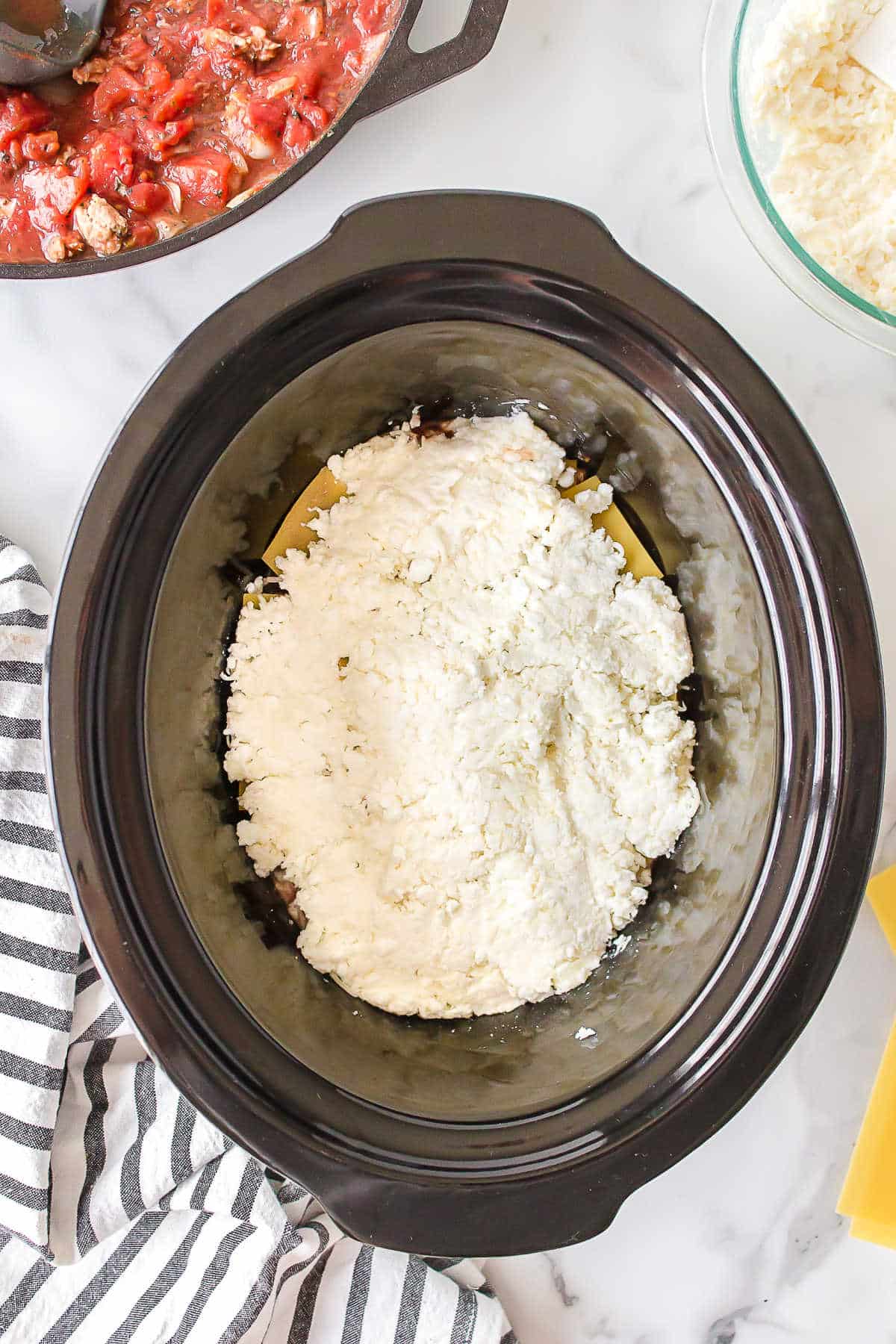 Cheese mixture on noodles in a slow cooker.