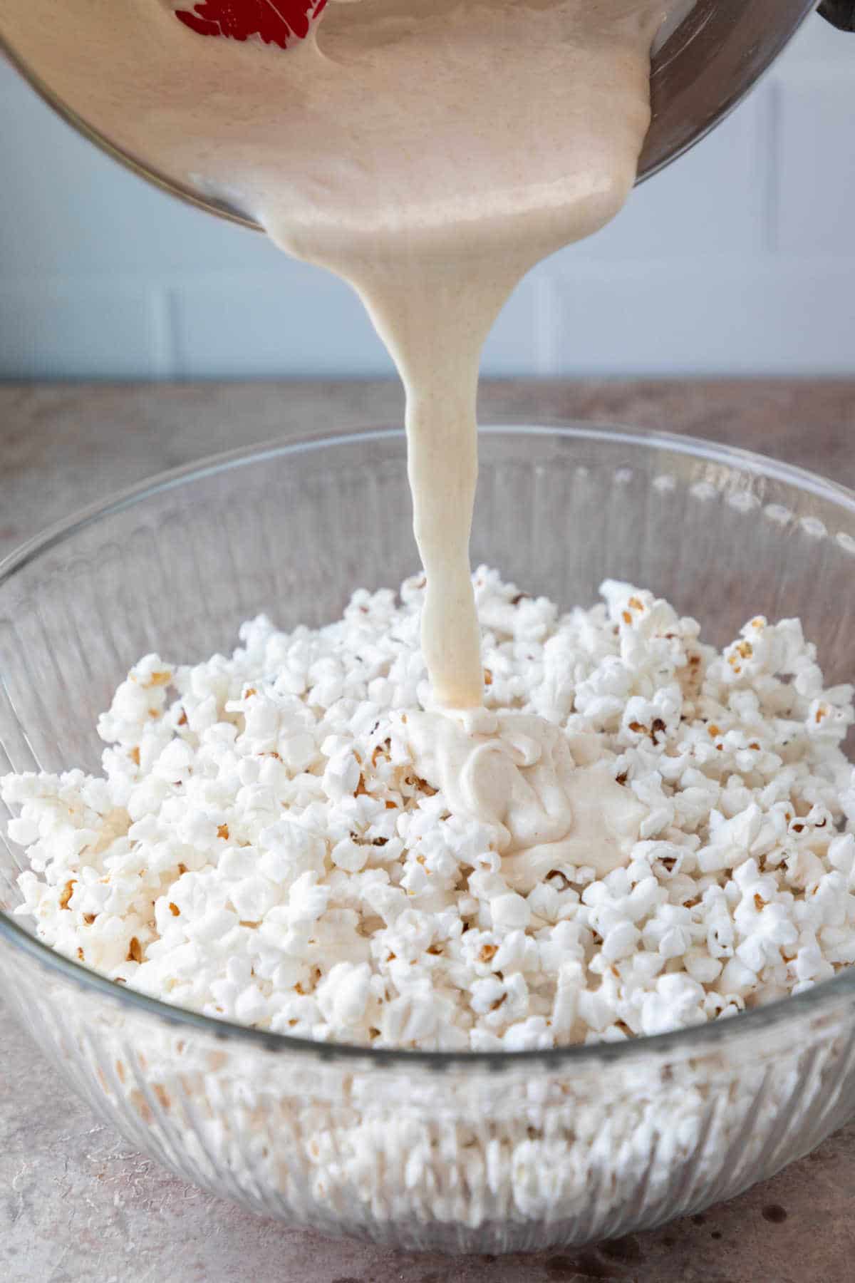 Melted marshmallow pouring into a bowl of popcorn.