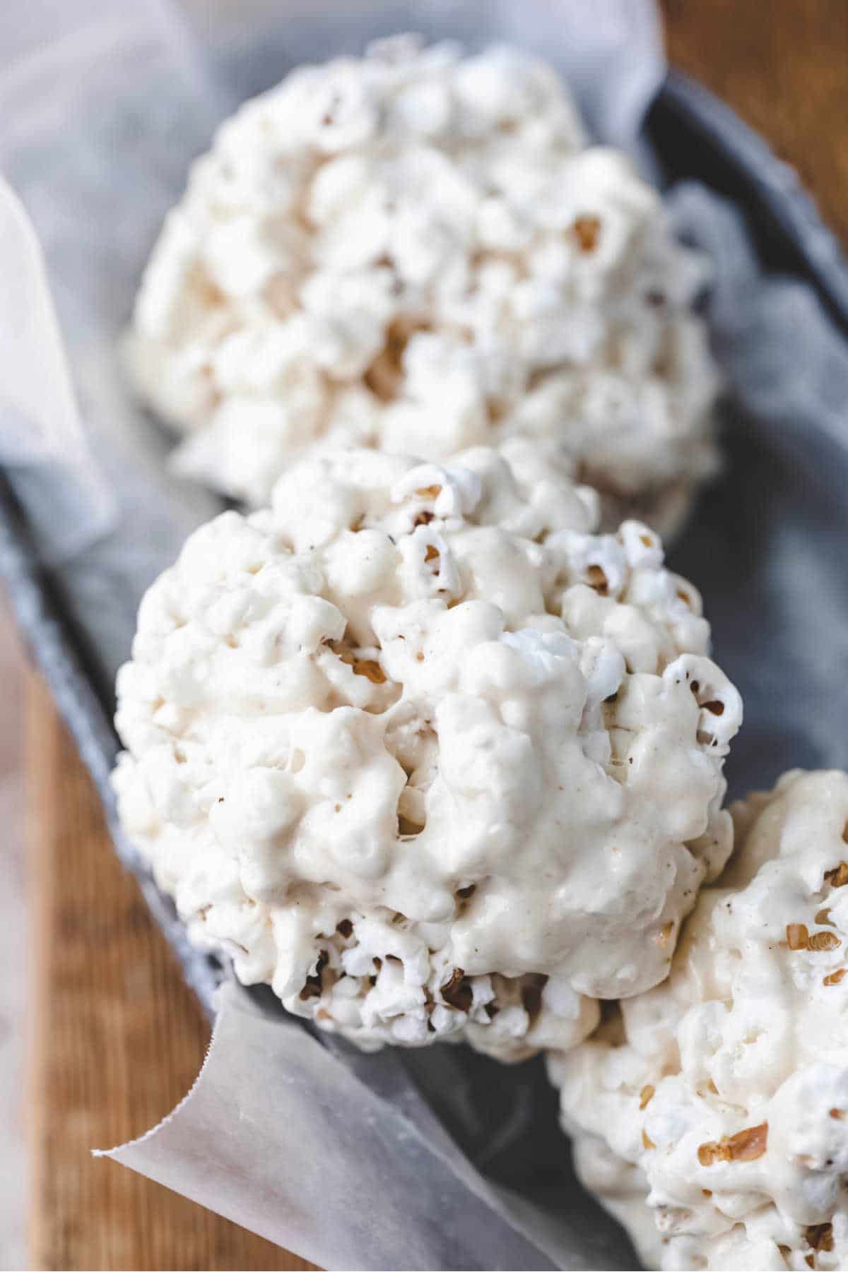 Three popcorn balls in wax paper.