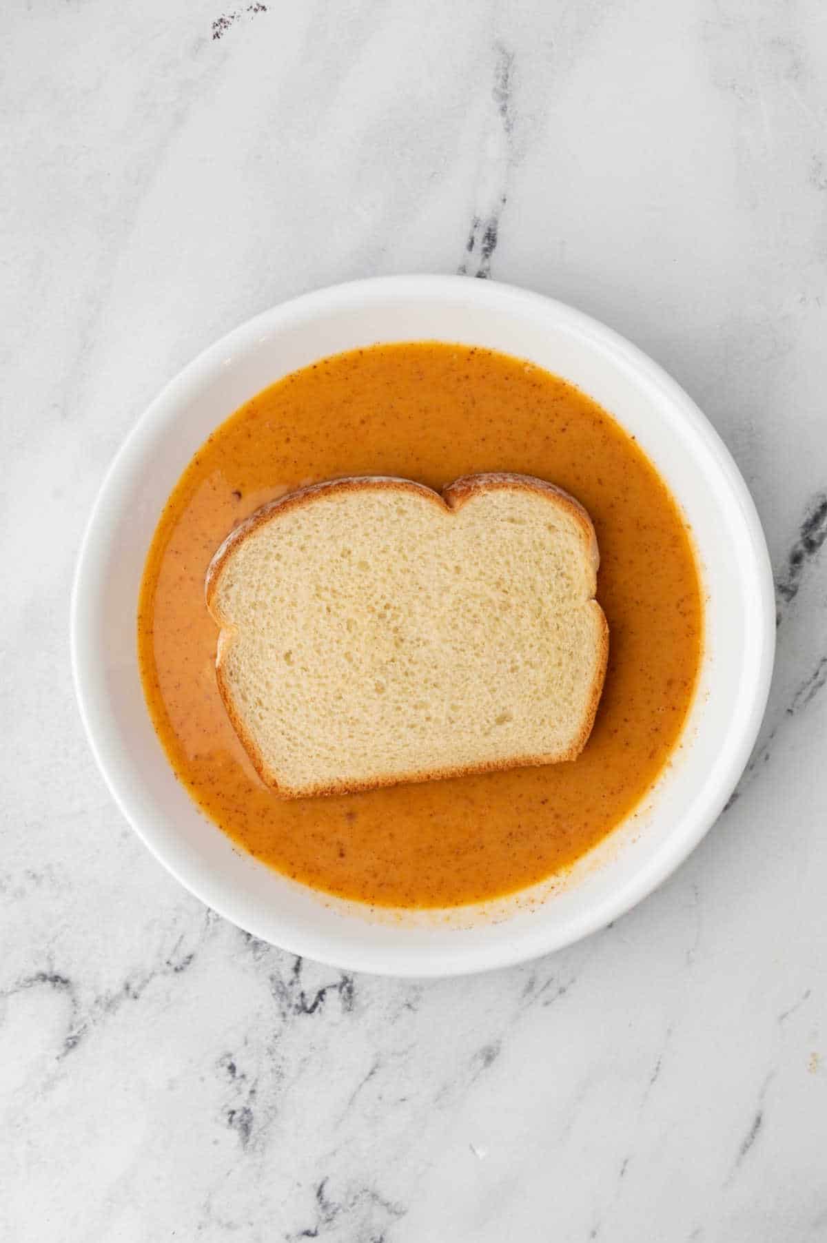 Shallow dish with bread in pumpkin mixture. 