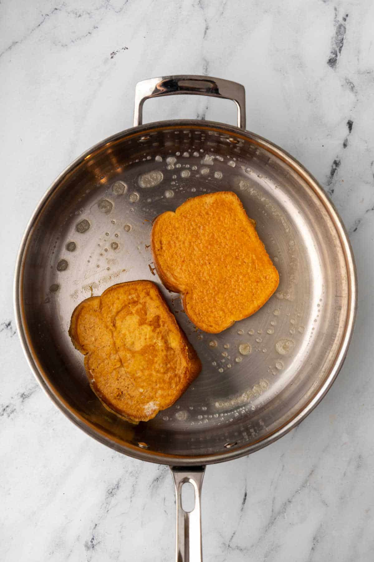 Pieces of pumpkin French toast cooking in a skillet.