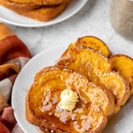 Plate of pumpkin French toast next to a stack of french toast.