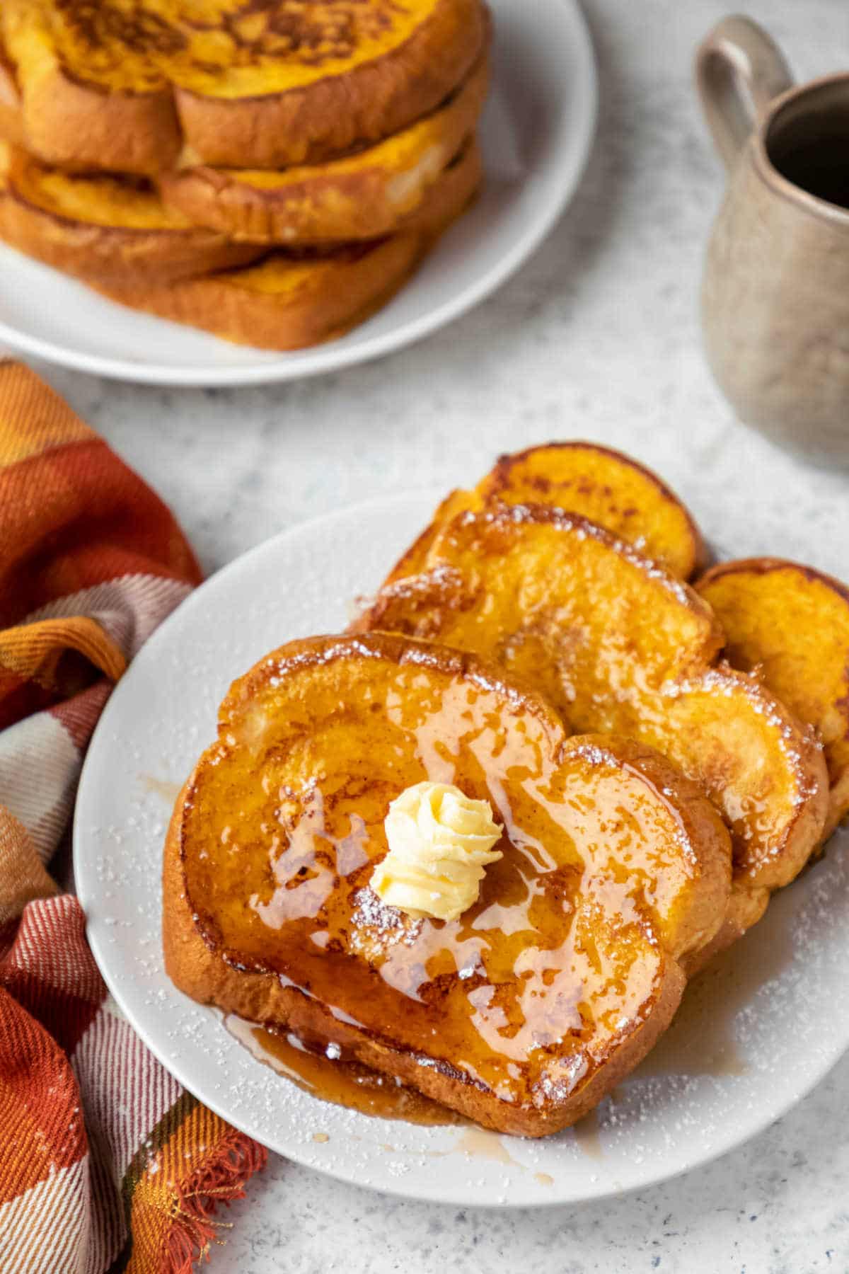 Plate of pumpkin French toast next to a stack of french toast. 