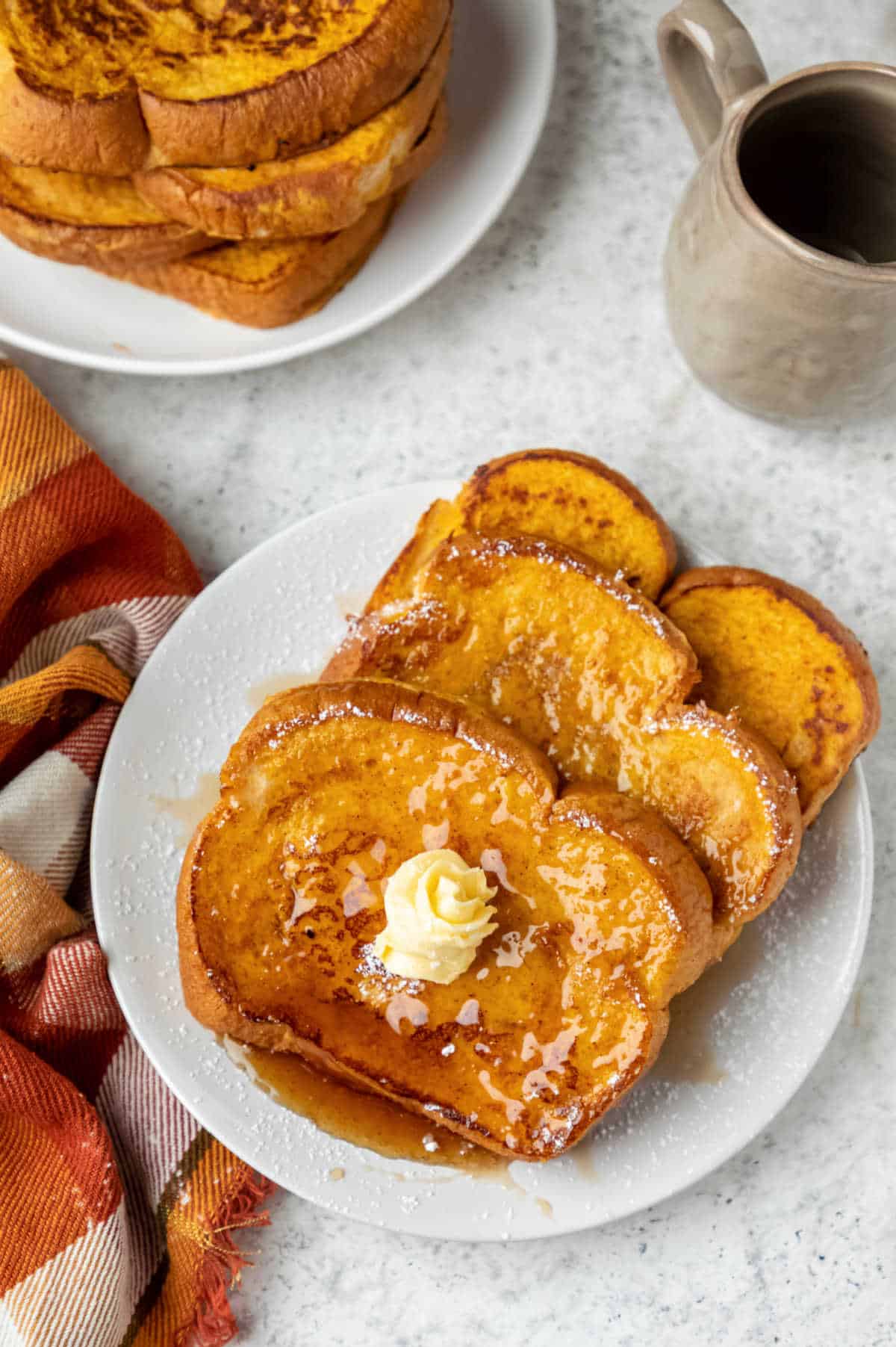 Three slices of pumpkin french toast topped with a pat of butter. 