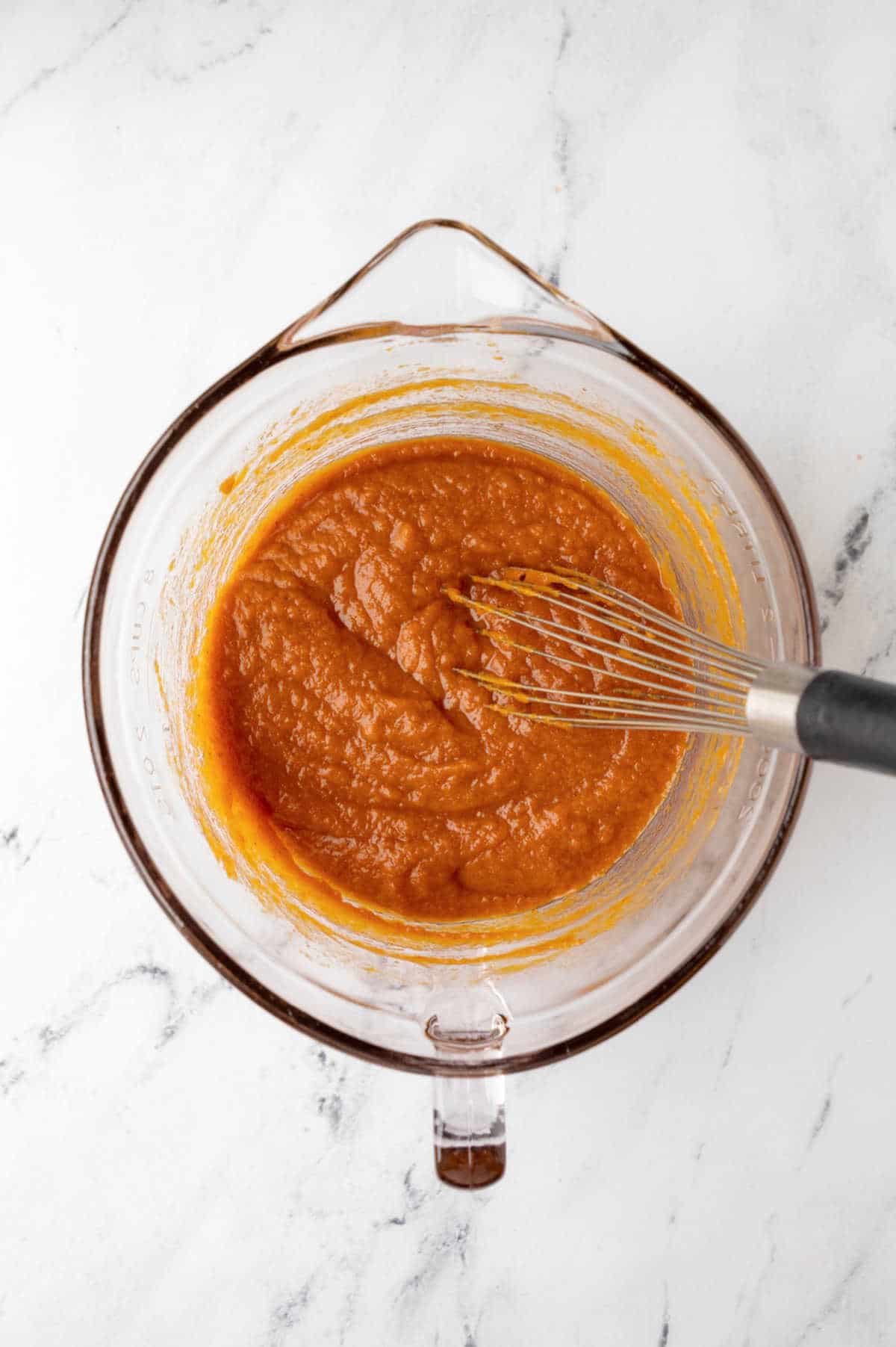 Pumpkin and sugars in a glass mixing bowl.