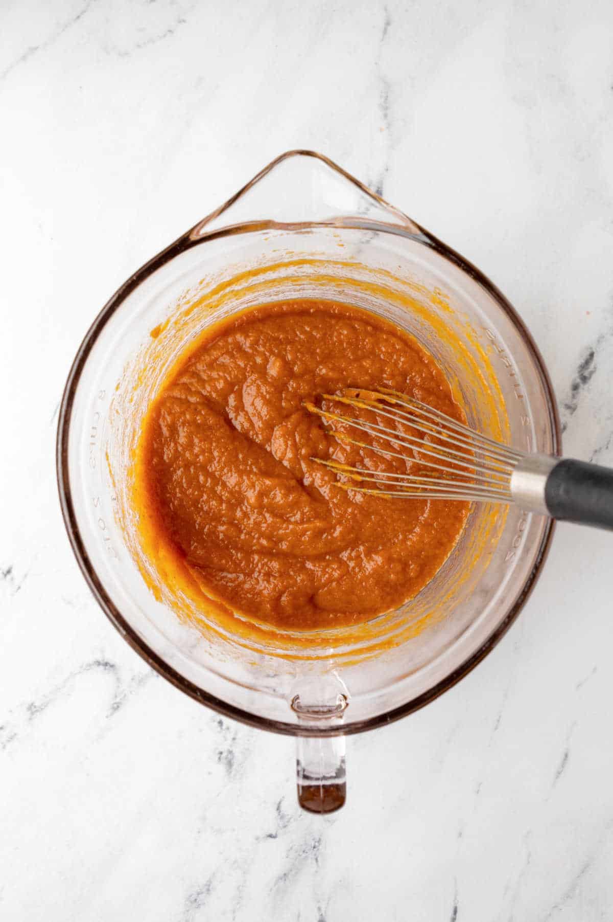 Pumpkin and sugars in a glass mixing bowl. 