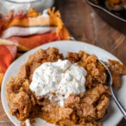 Plate of pumpkin pie crisp topped with whipped cream and cinnamon.