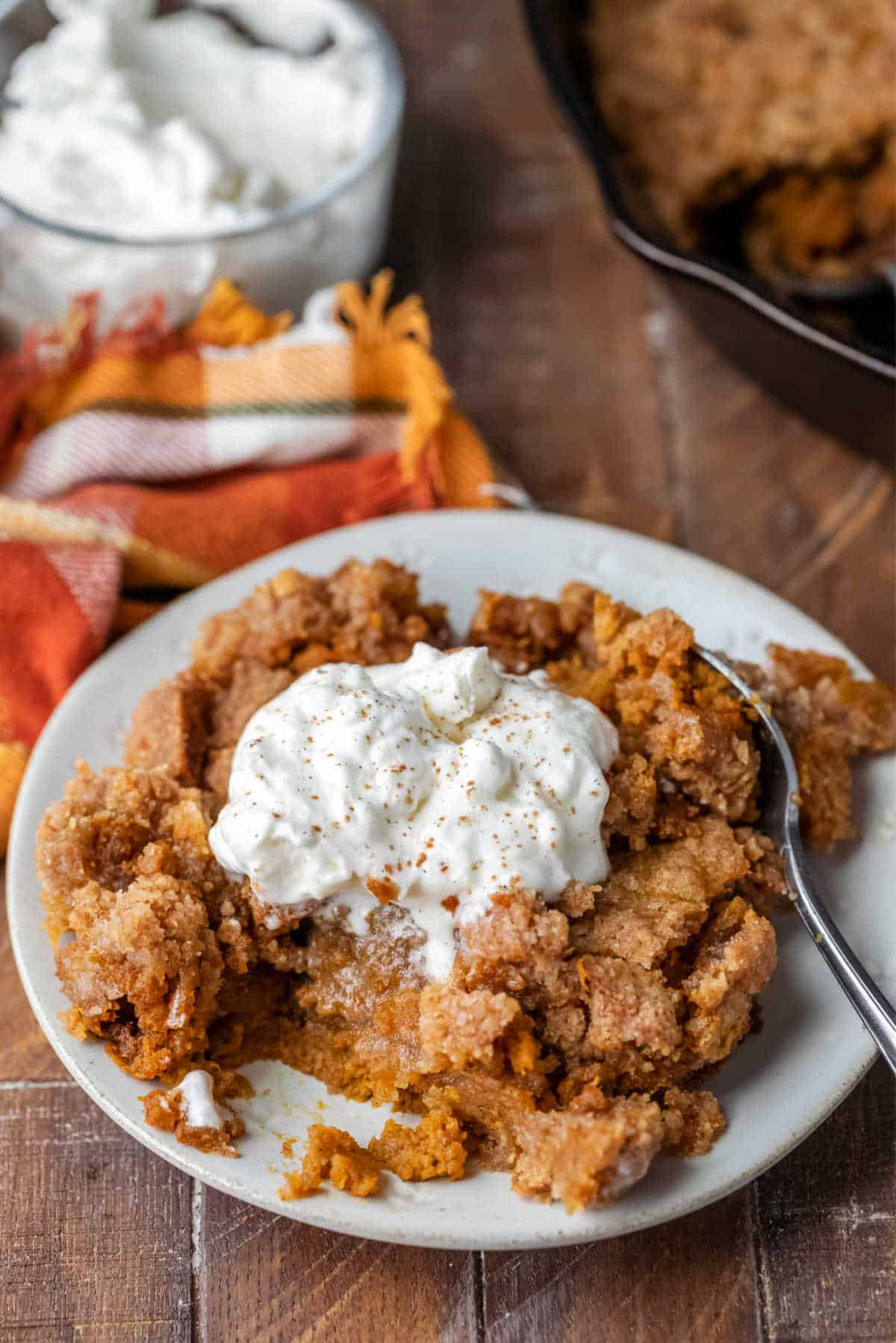 Plate of pumpkin pie crisp topped with whipped cream and cinnamon. 