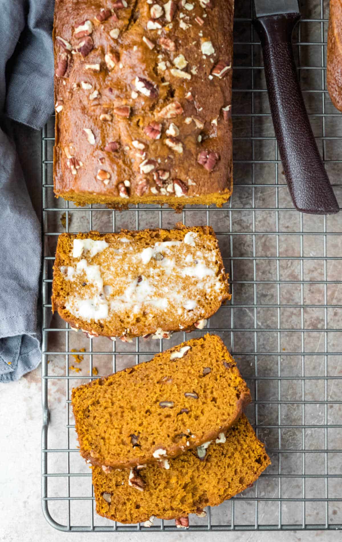 A loaf of pumpkin nut bread next to a bread knife. 