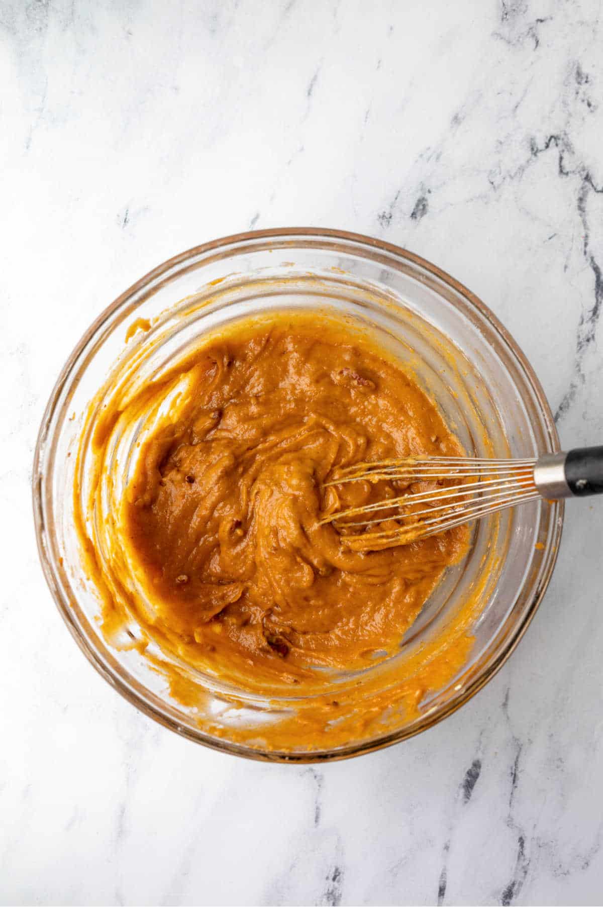 Pumpkin nut bread batter in a glass mixing bowl. 