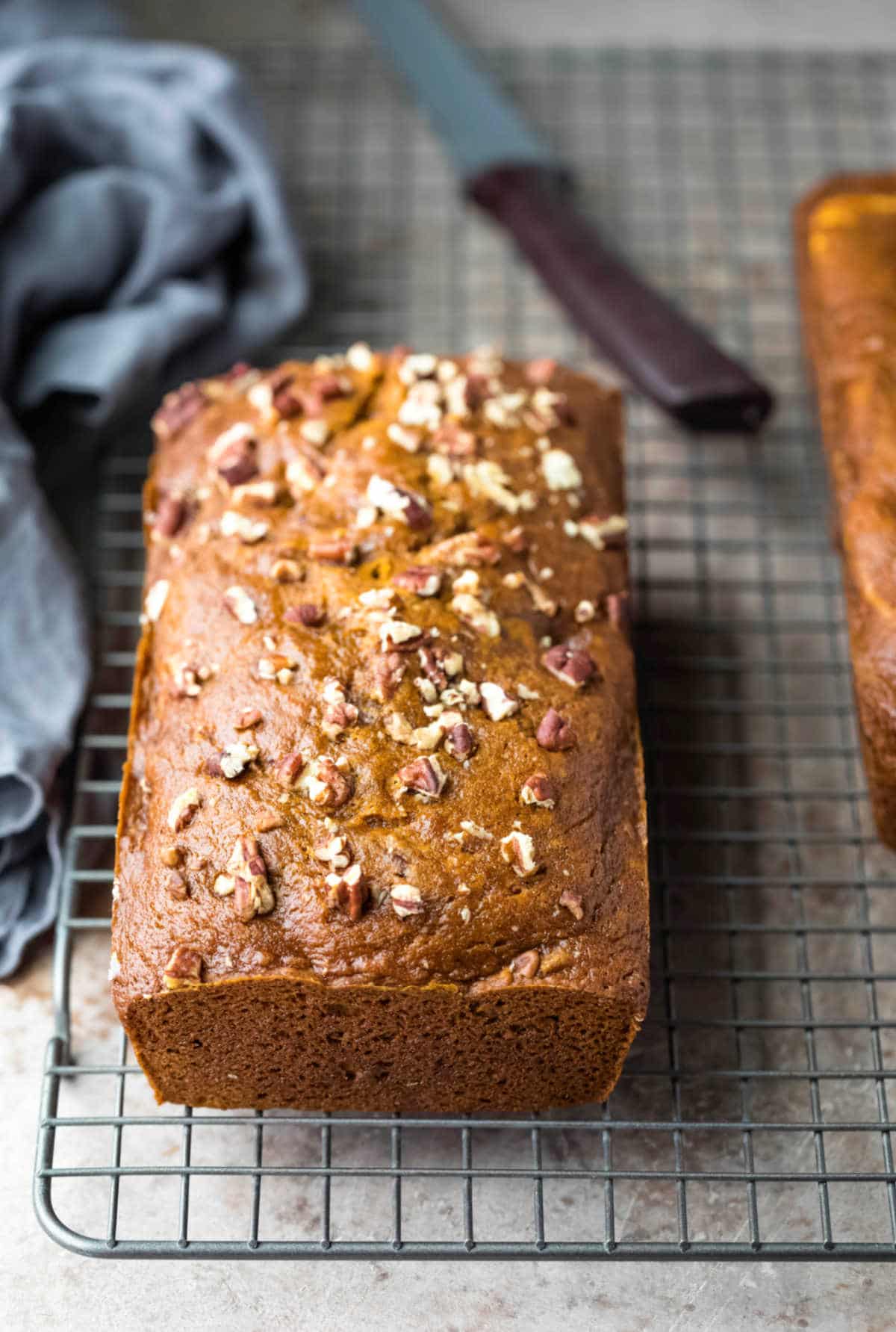 Loaf of pumpkin nut bread on a wire cooling rack.