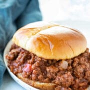 Sloppy joe on a plate next to a blue napkin.