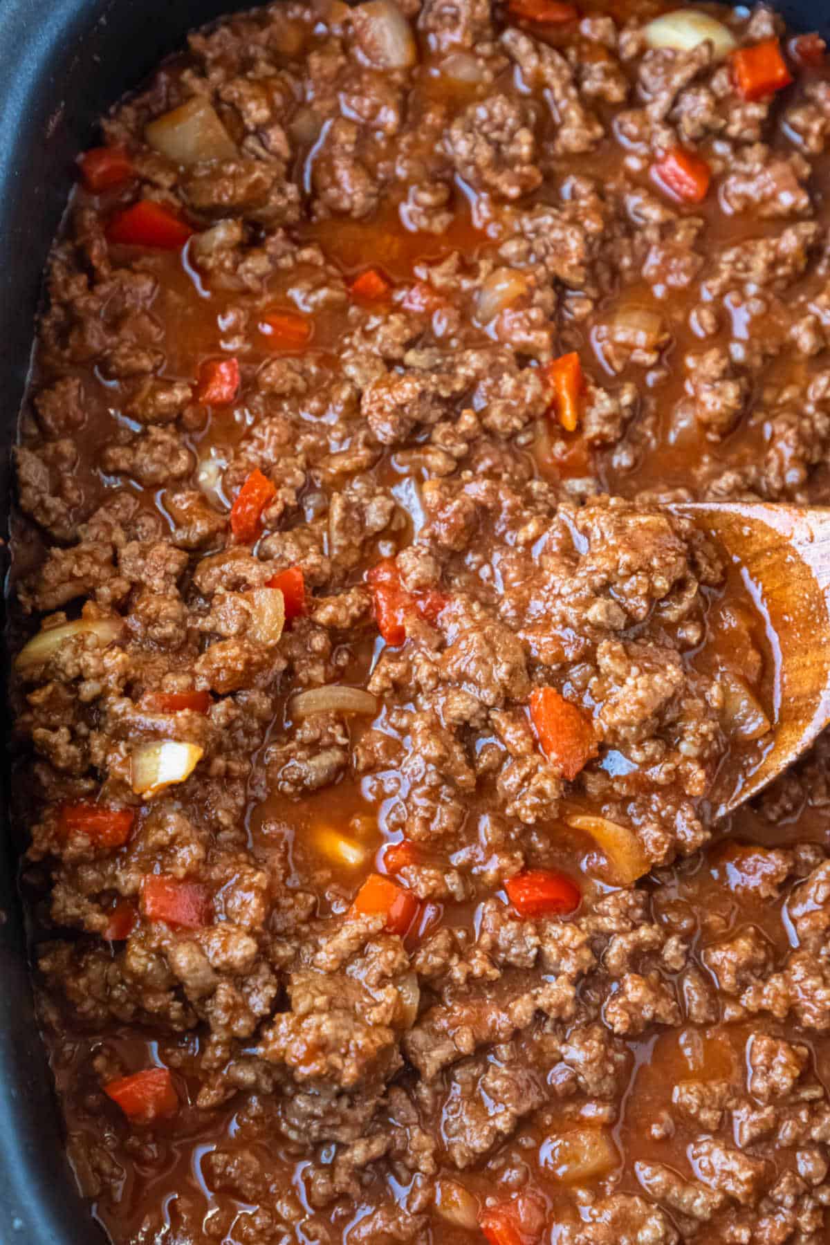 Wooden spoon holding a scoop of sloppy joe mix. 